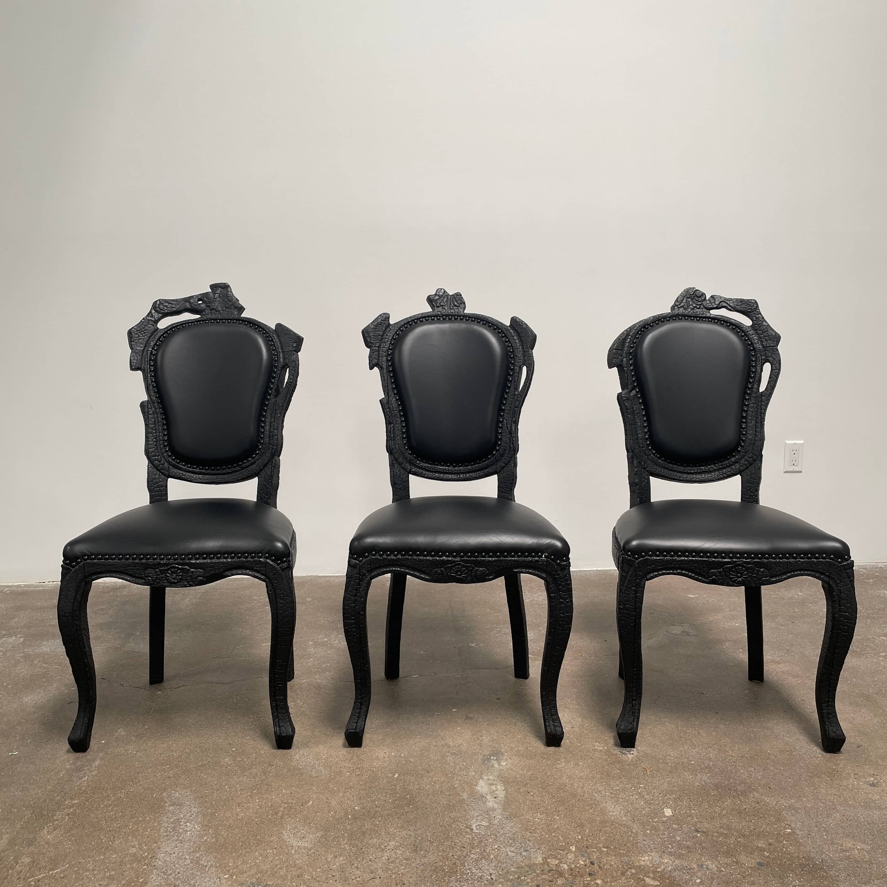 A set of seven Moooi Smoke Dining Side Chairs, crafted by Moooi in an ornate black finish with leather upholstery and cushioned seats and backs, arranged in two rows against a plain white background.