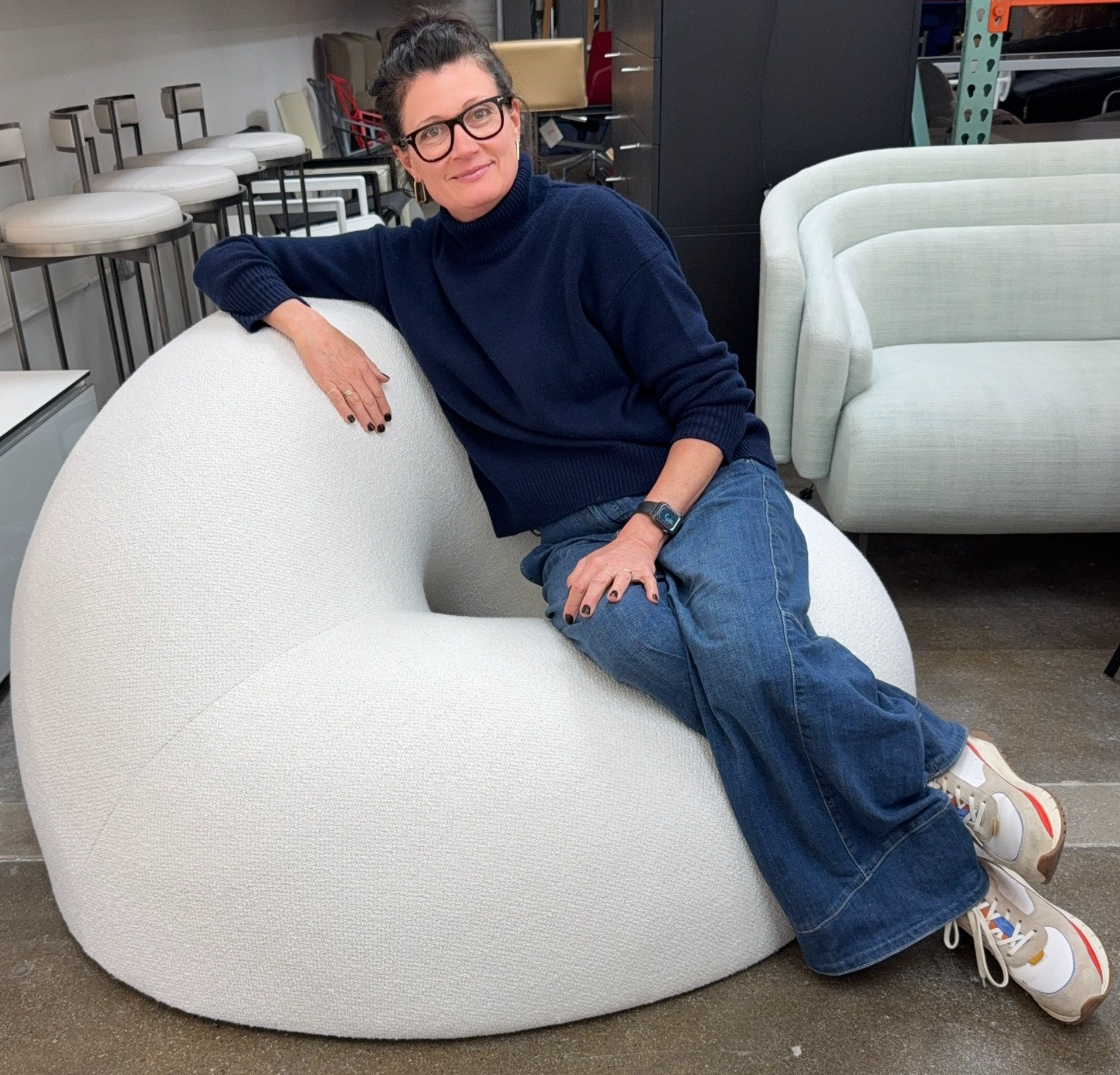 The Objects of Common Interest Tube Chair by Objects of Common Interest is a modern, light grey lounge chair with a donut-shaped design, rounded form, and central indentation, shown against a plain white background.