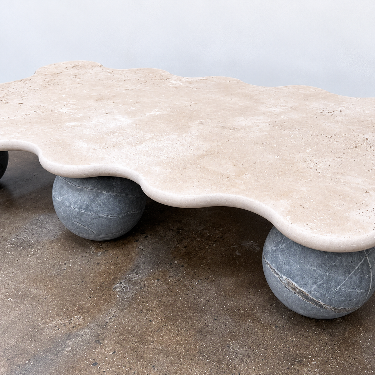 Form(LA) Palla Rectangle Coffee Table with a wavy-edged stone top supported by three spherical stone legs.