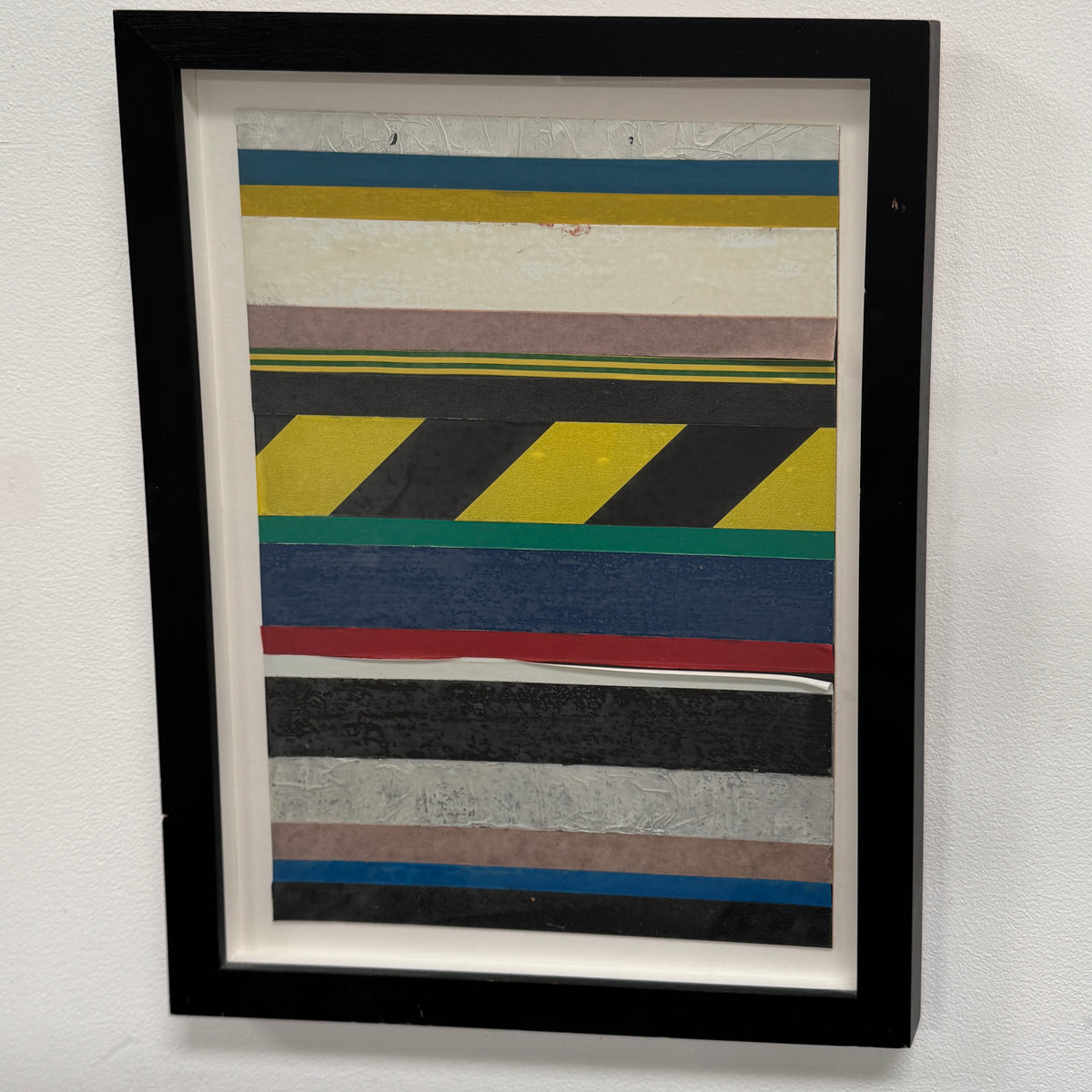 Oscar Berglund Framed Art by Modern Resale shows horizontal colored stripes and a yellow-black diagonal caution stripe, mounted on a white wall.