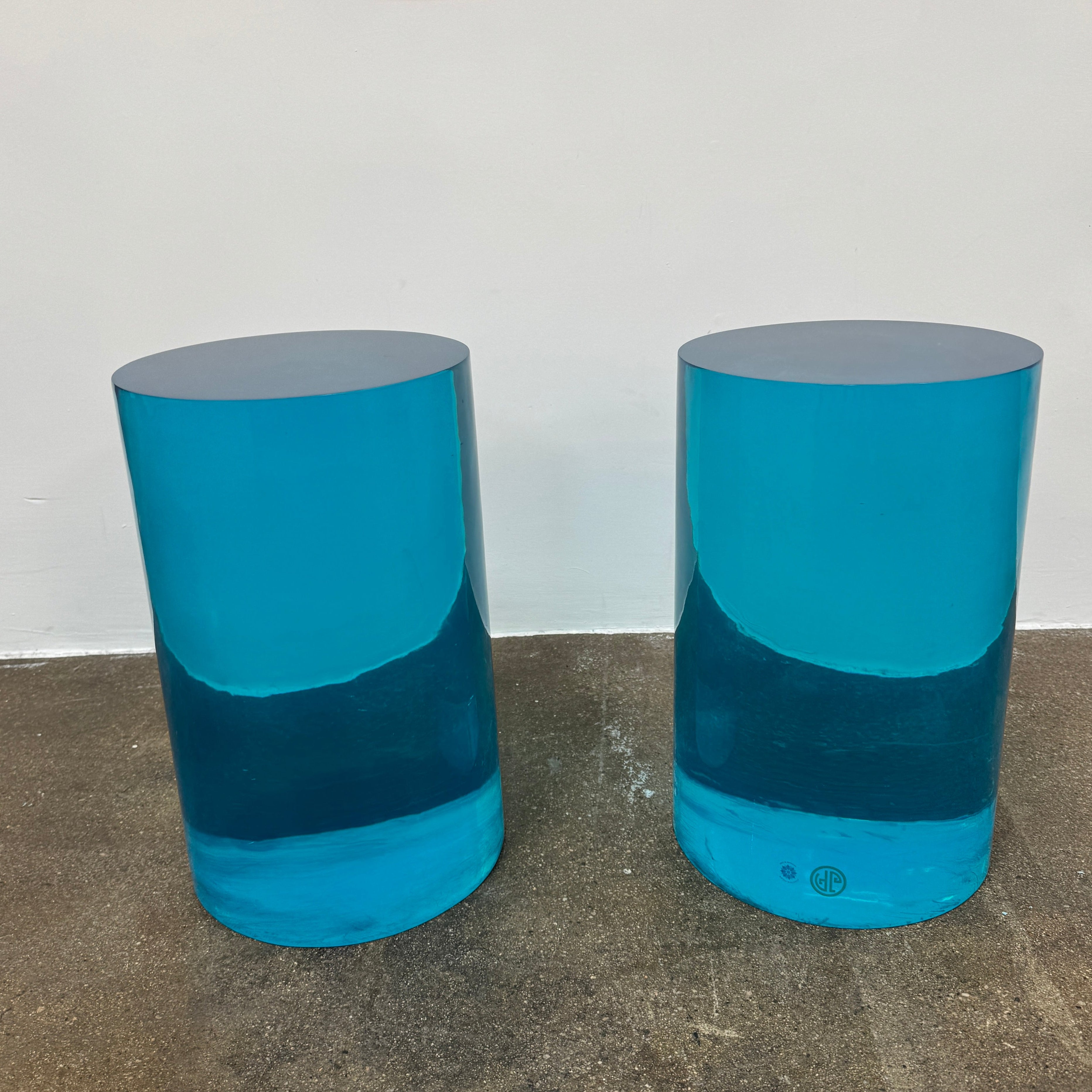 The Jonathan Adler blue acrylic cylindrical table stands upright on a white background, featuring smooth sides and a flat top that evoke the brand’s modern, chic design aesthetic.