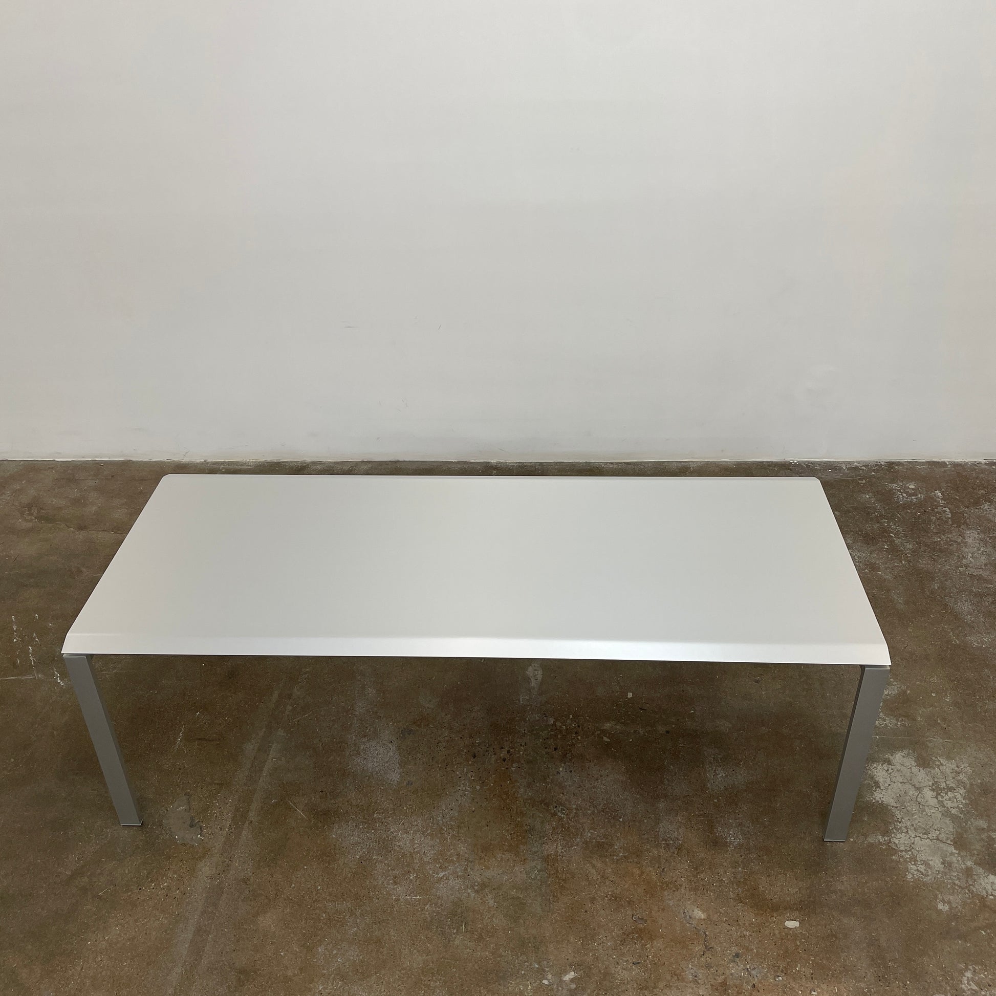 The Pallucco Italia Little Wing Dining Table features a sleek rectangular white top and four straight metal legs—an elegant aluminum dining table by Pallucco Italia, perfect for modern interiors.