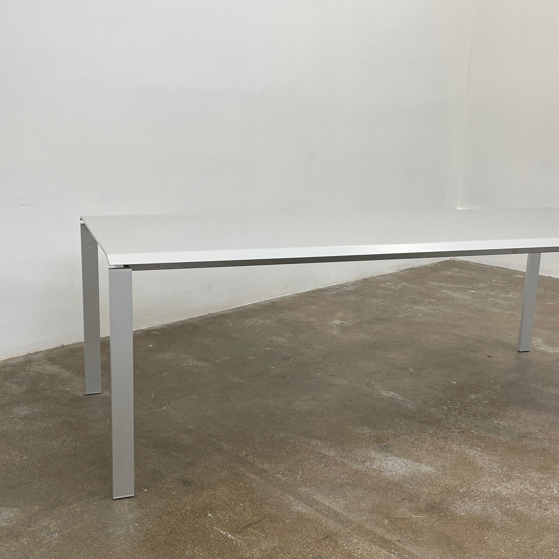 The Pallucco Italia Little Wing Dining Table features a sleek rectangular white top and four straight metal legs—an elegant aluminum dining table by Pallucco Italia, perfect for modern interiors.