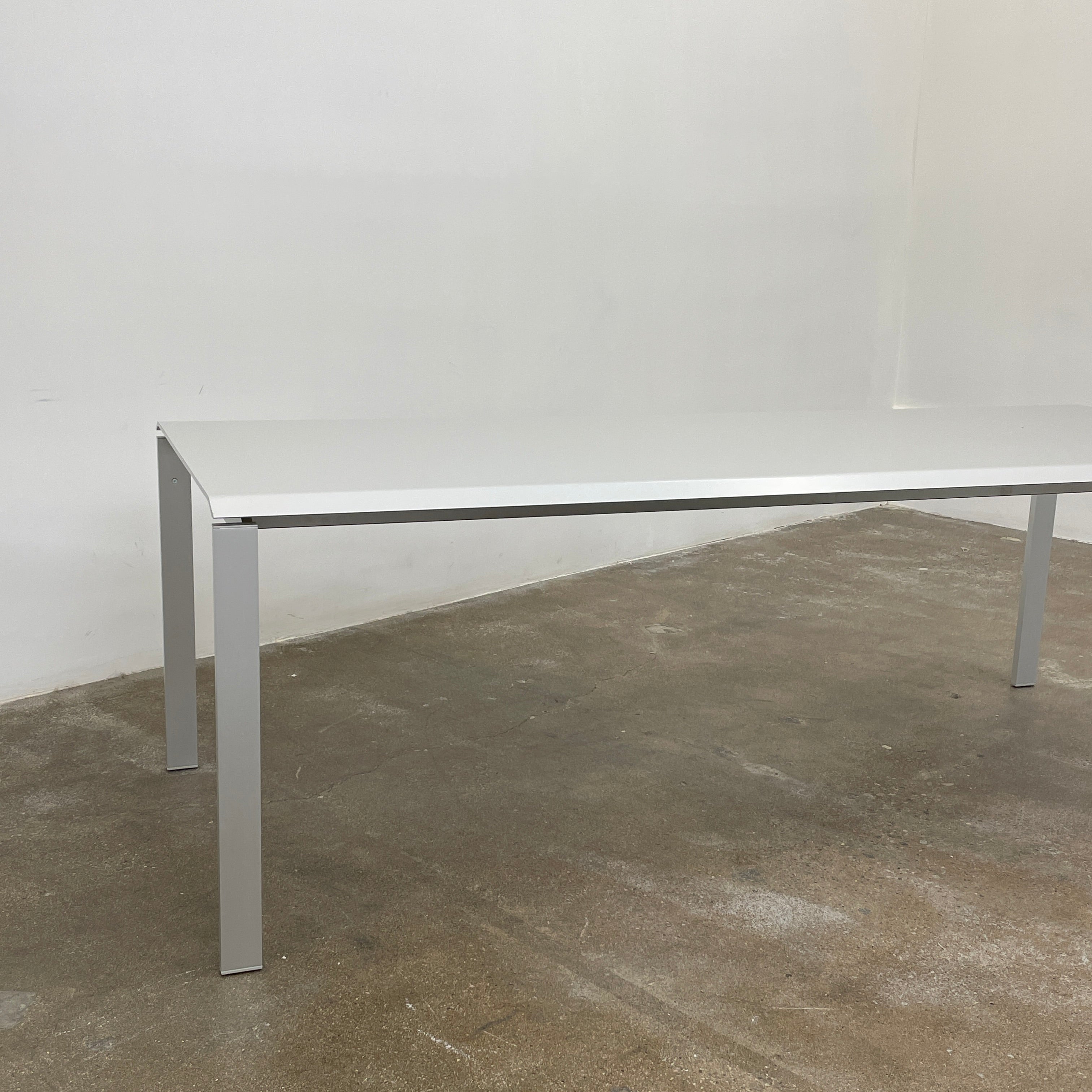 The Pallucco Italia Little Wing Dining Table features a sleek rectangular white top and four straight metal legs—an elegant aluminum dining table by Pallucco Italia, perfect for modern interiors.