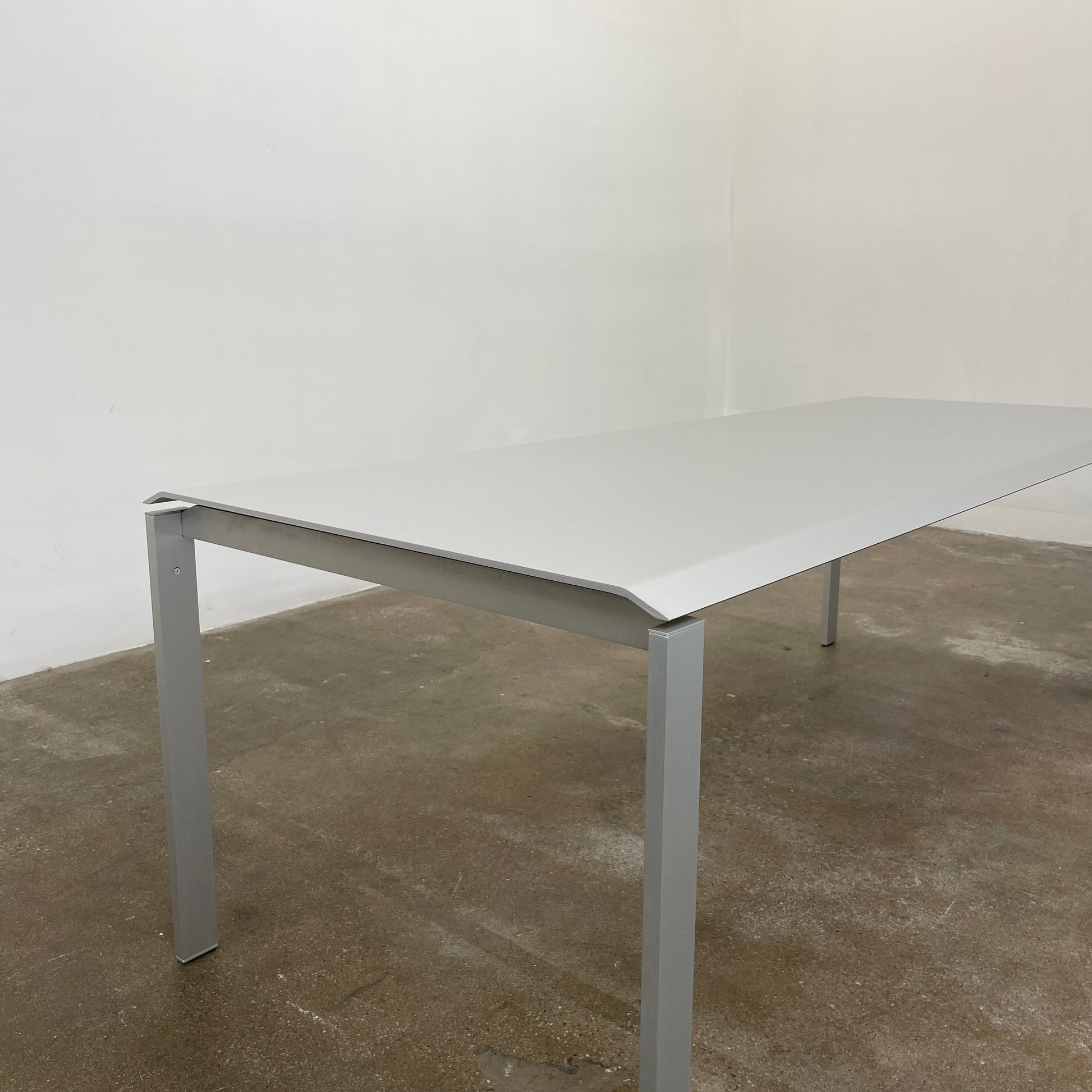 The Pallucco Italia Little Wing Dining Table features a sleek rectangular white top and four straight metal legs—an elegant aluminum dining table by Pallucco Italia, perfect for modern interiors.