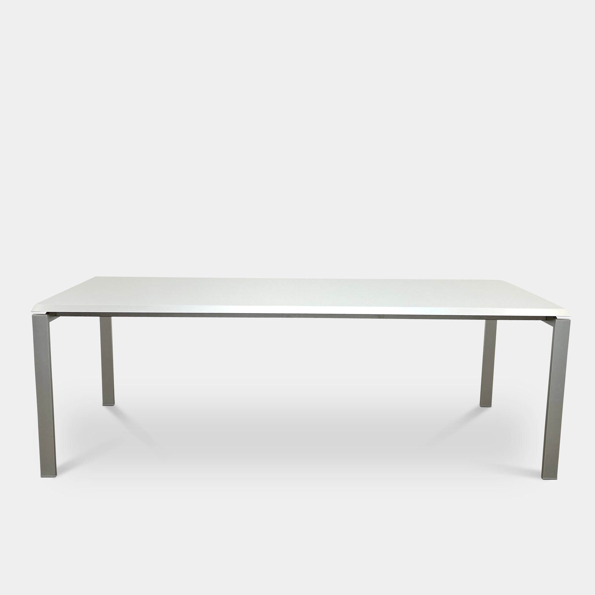 The Pallucco Italia Little Wing Dining Table features a sleek rectangular white top and four straight metal legs—an elegant aluminum dining table by Pallucco Italia, perfect for modern interiors.