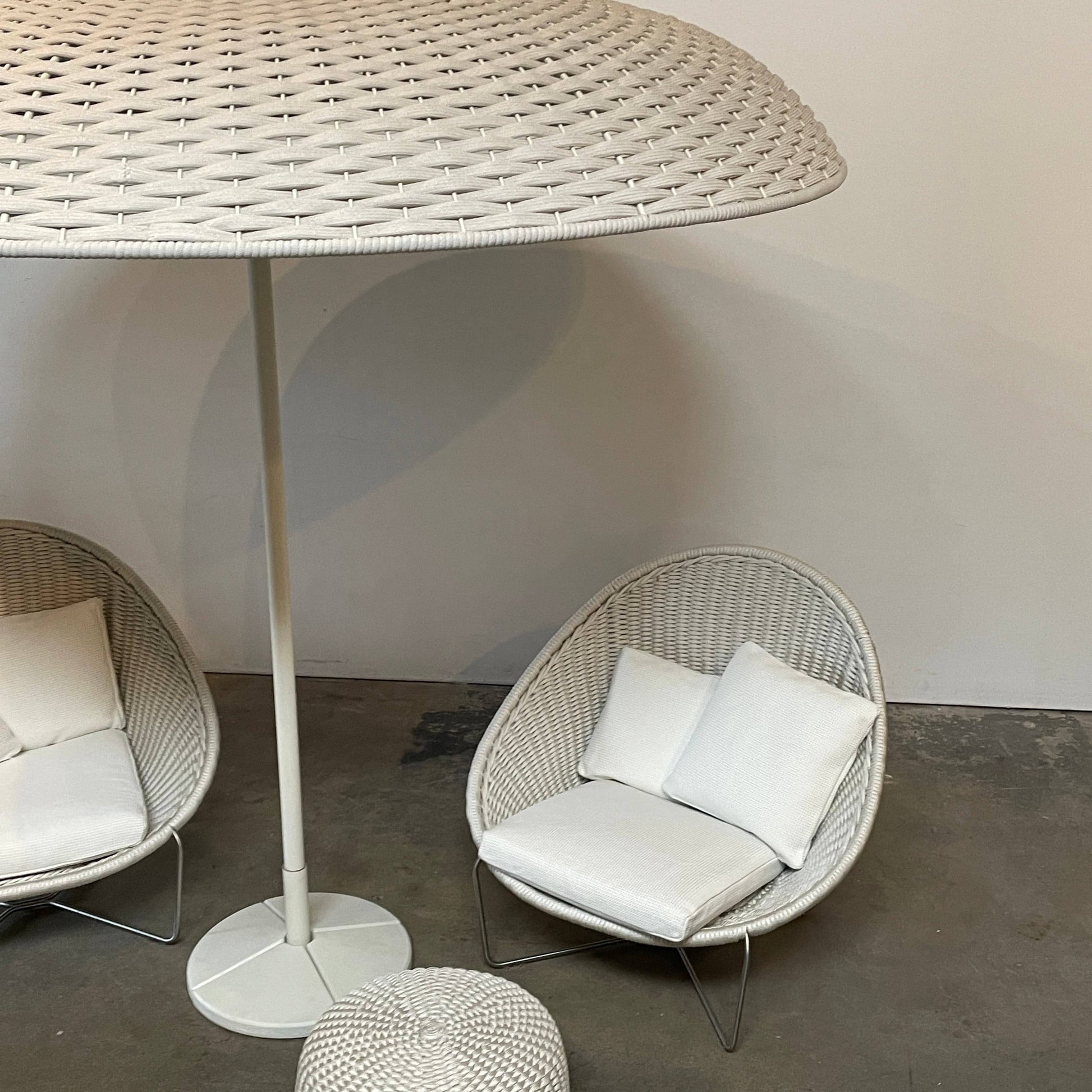 A Paola Lenti Mogambo Parasol on a white stand, designed by Paola Lenti.