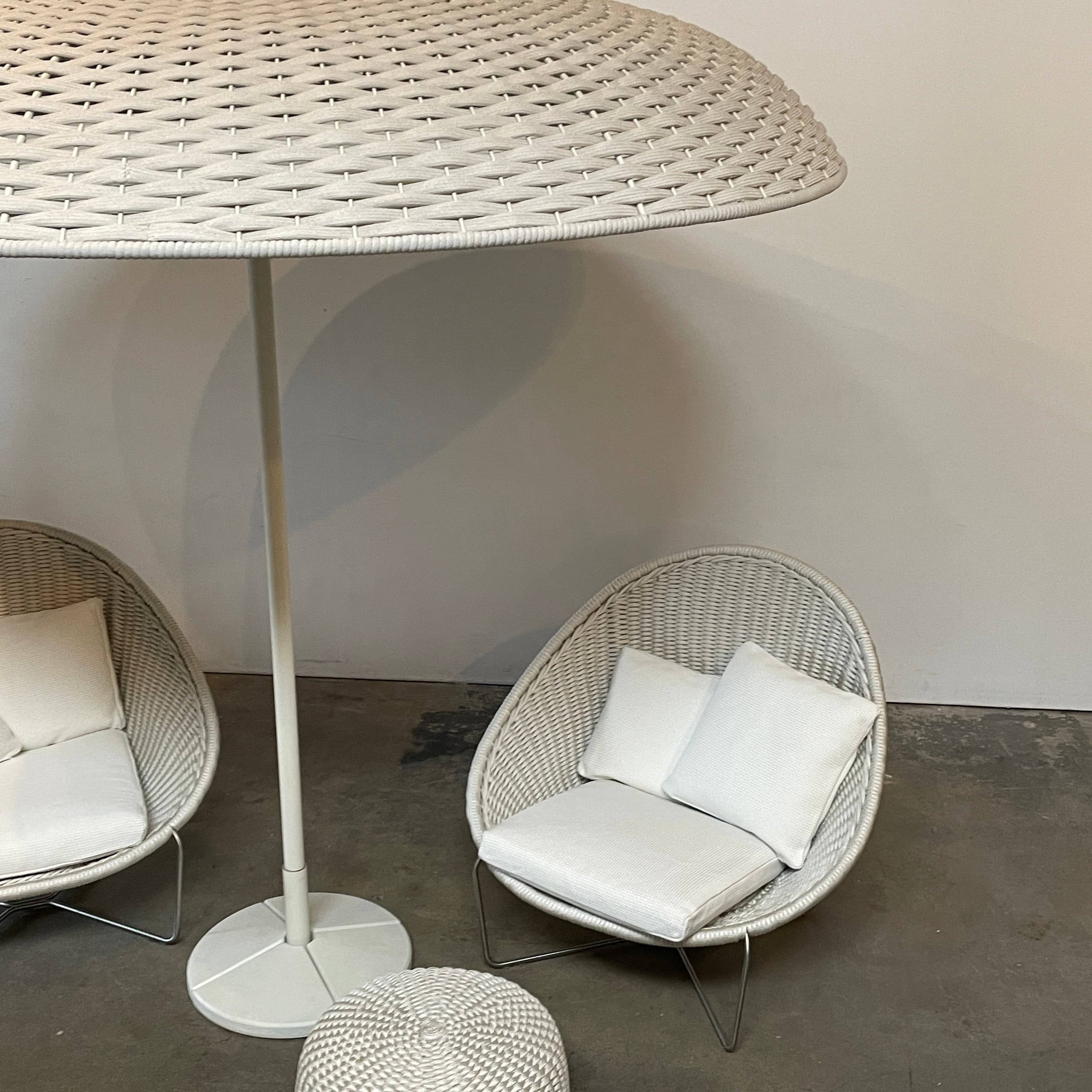 A Paola Lenti Mogambo Parasol on a white stand, designed by Paola Lenti.