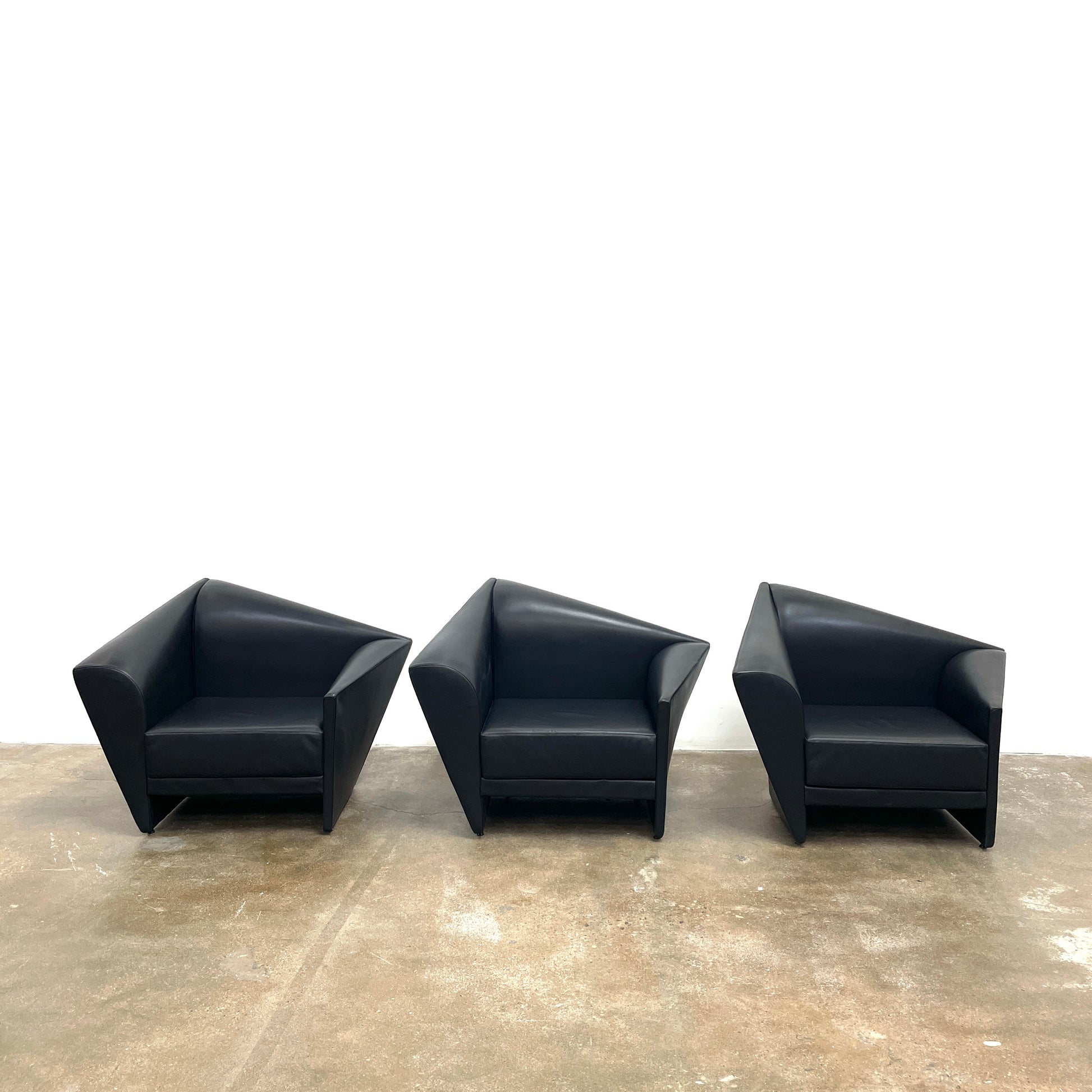 The Lilly of the Wind Armchair by Paolo Pallucco and Mireille Rivier for Pallucco Italia showcases a black leather finish and angular, modern design on a light gray background, echoing Paolo Pallucco's post-modern style.