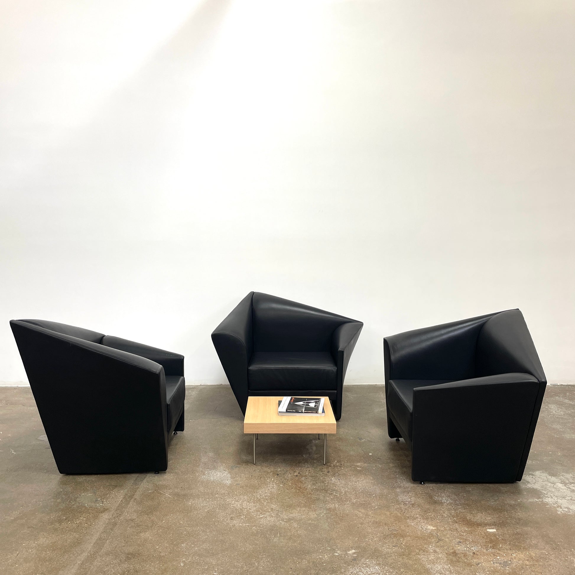 The Lilly of the Wind Armchair by Paolo Pallucco and Mireille Rivier for Pallucco Italia showcases a black leather finish and angular, modern design on a light gray background, echoing Paolo Pallucco's post-modern style.