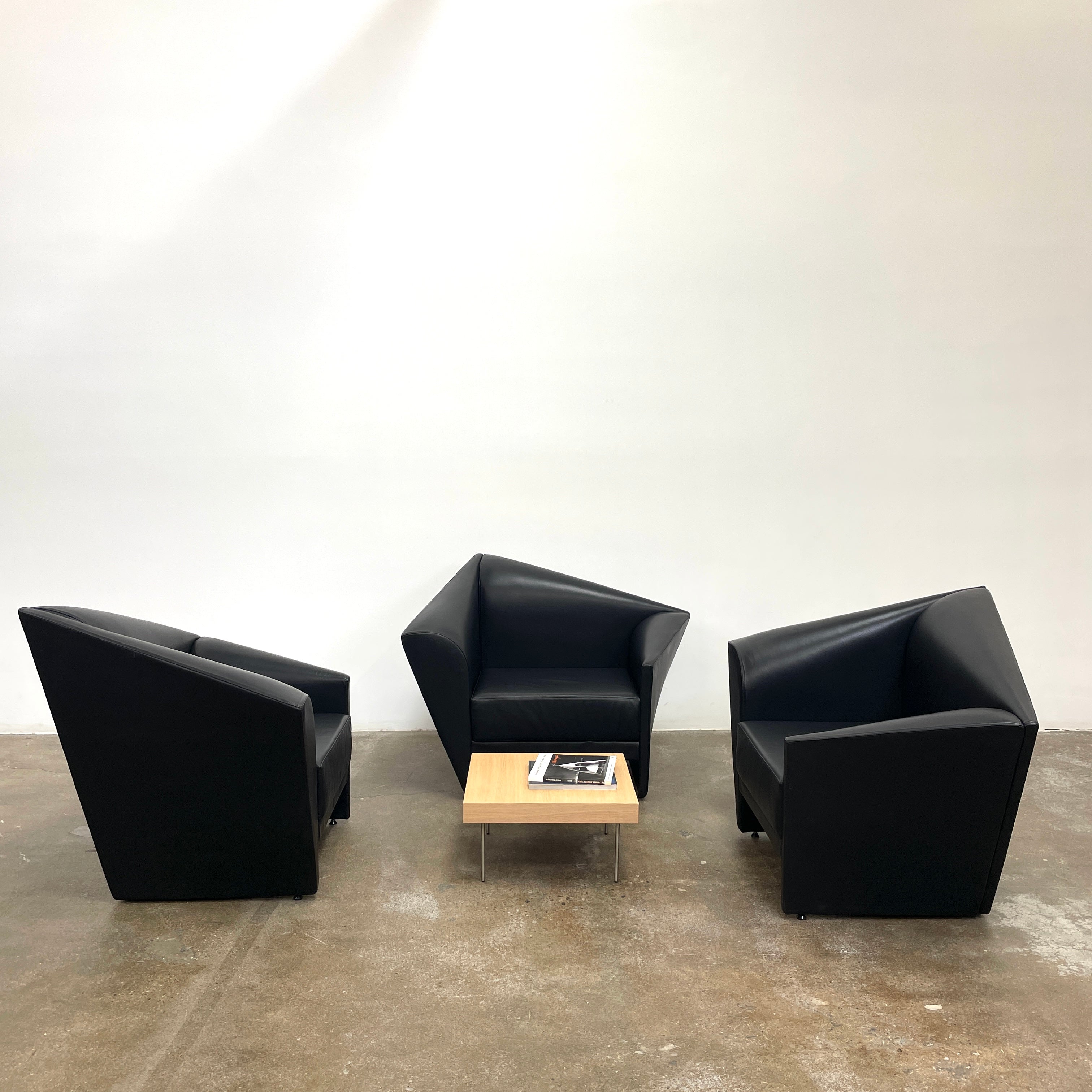 The Lilly of the Wind Armchair by Paolo Pallucco and Mireille Rivier for Pallucco Italia showcases a black leather finish and angular, modern design on a light gray background, echoing Paolo Pallucco's post-modern style.