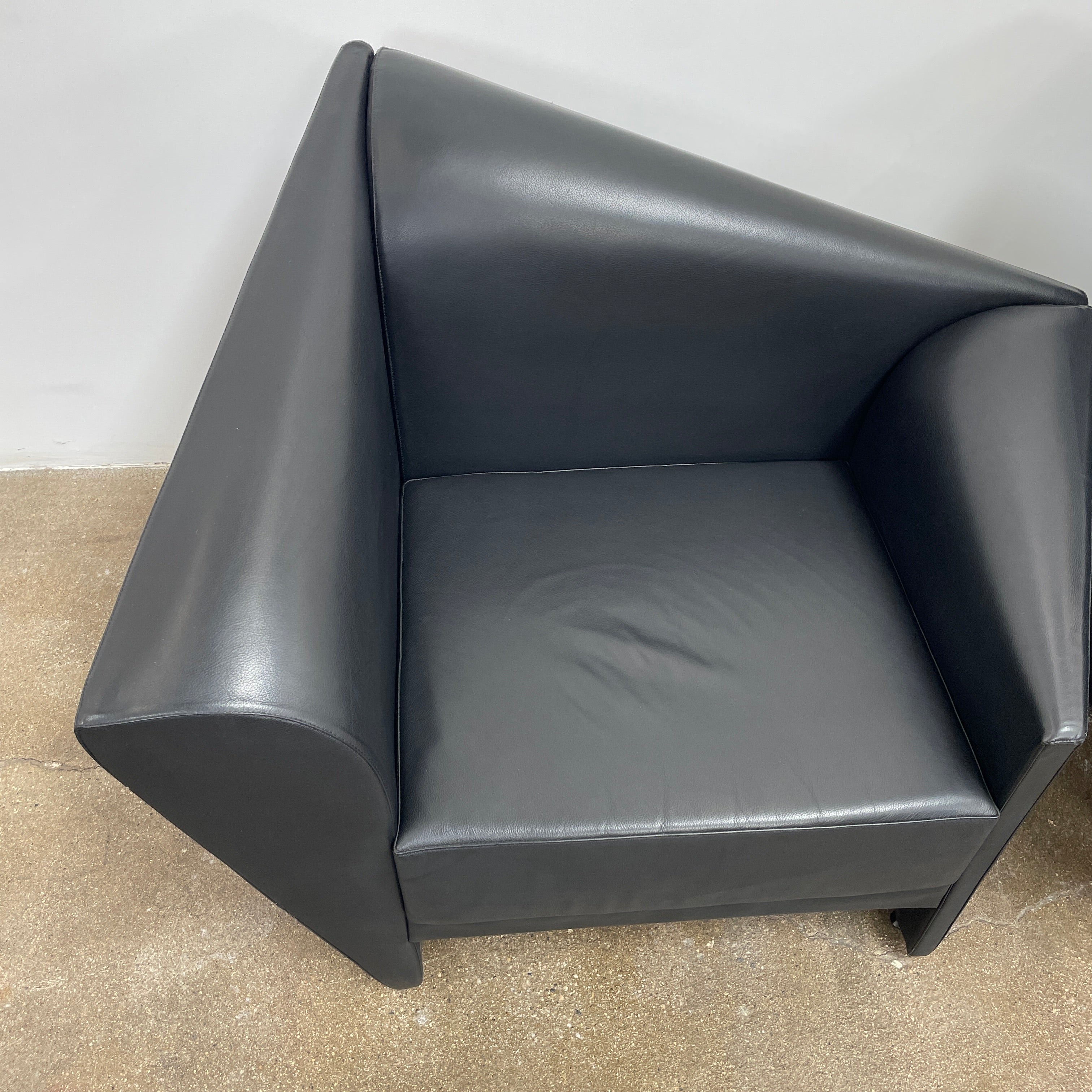 The Lilly of the Wind Armchair by Paolo Pallucco and Mireille Rivier for Pallucco Italia showcases a black leather finish and angular, modern design on a light gray background, echoing Paolo Pallucco's post-modern style.