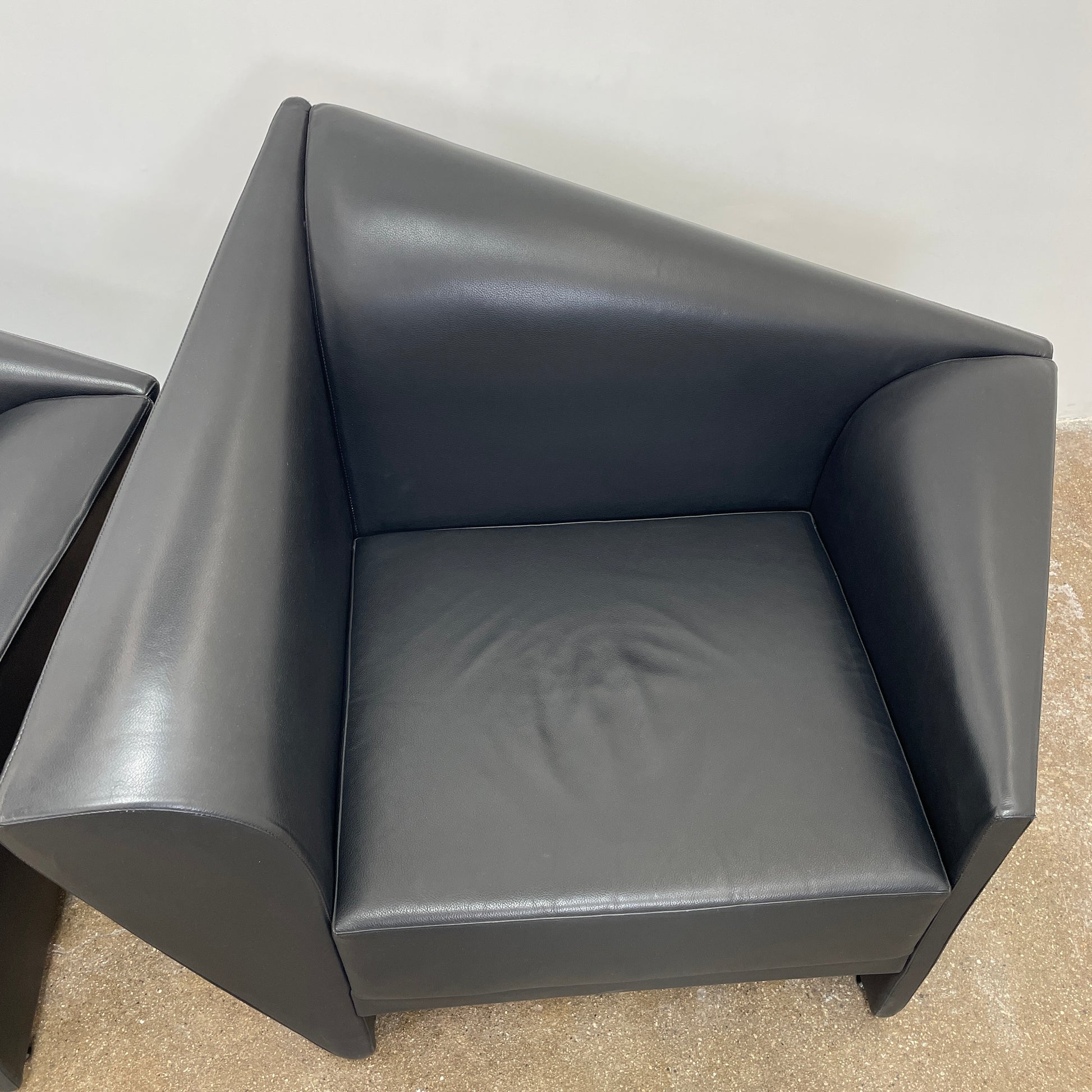 The Lilly of the Wind Armchair by Paolo Pallucco and Mireille Rivier for Pallucco Italia showcases a black leather finish and angular, modern design on a light gray background, echoing Paolo Pallucco's post-modern style.