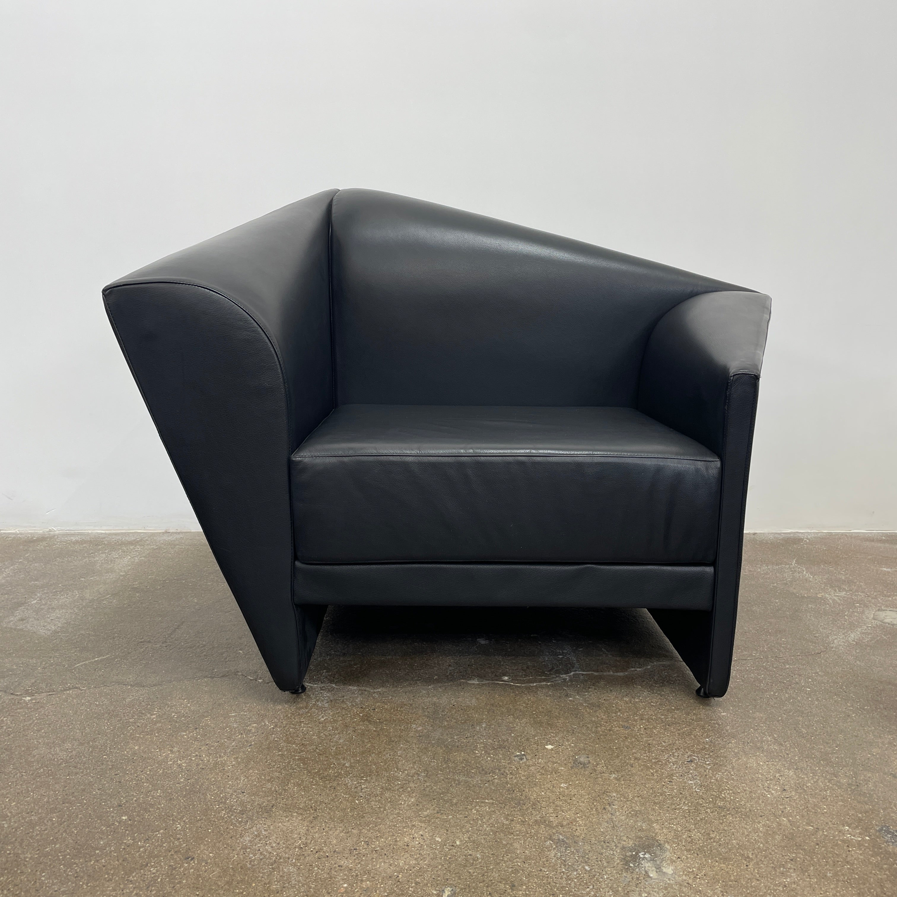 The Lilly of the Wind Armchair by Paolo Pallucco and Mireille Rivier for Pallucco Italia showcases a black leather finish and angular, modern design on a light gray background, echoing Paolo Pallucco's post-modern style.