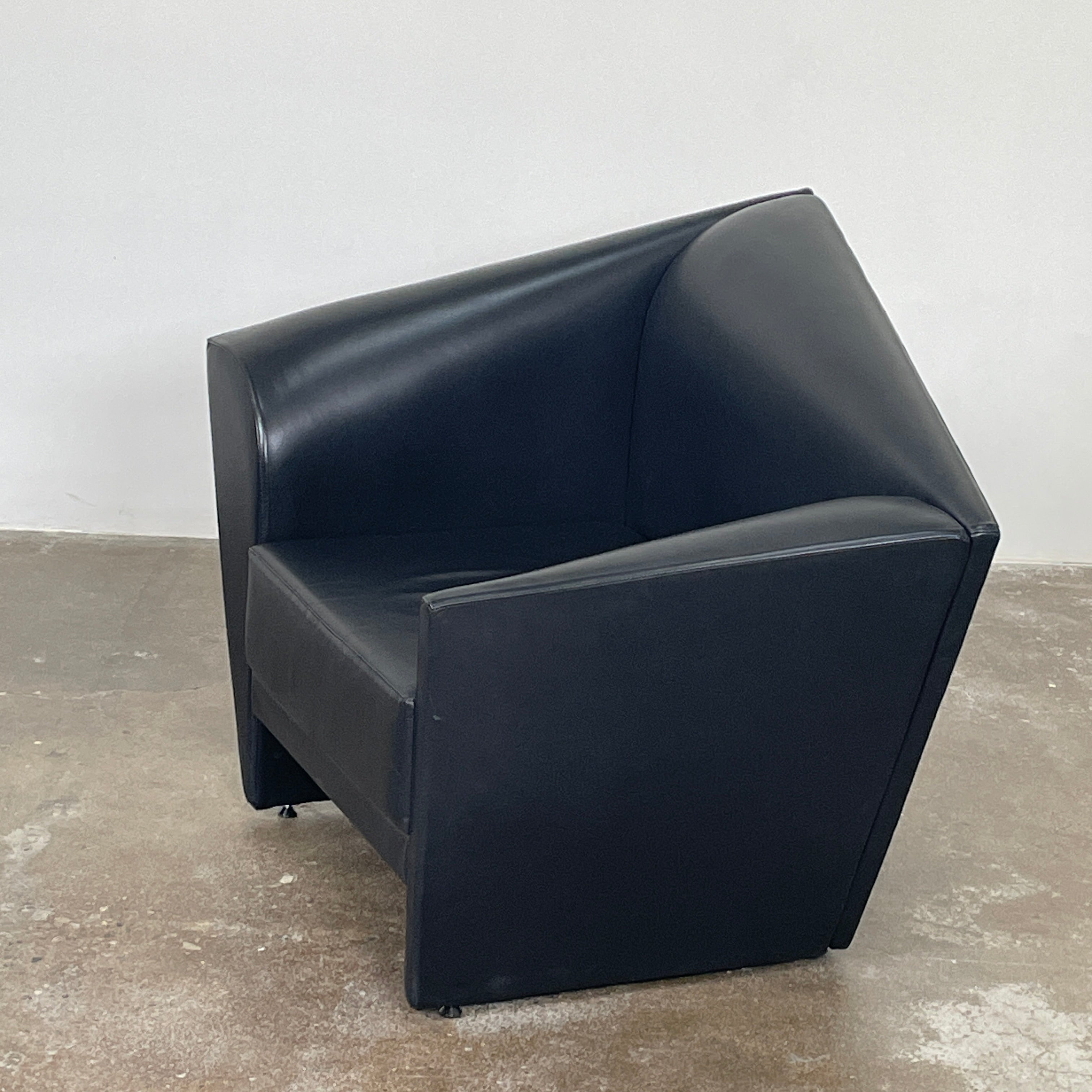 The Lilly of the Wind Armchair by Paolo Pallucco and Mireille Rivier for Pallucco Italia showcases a black leather finish and angular, modern design on a light gray background, echoing Paolo Pallucco's post-modern style.