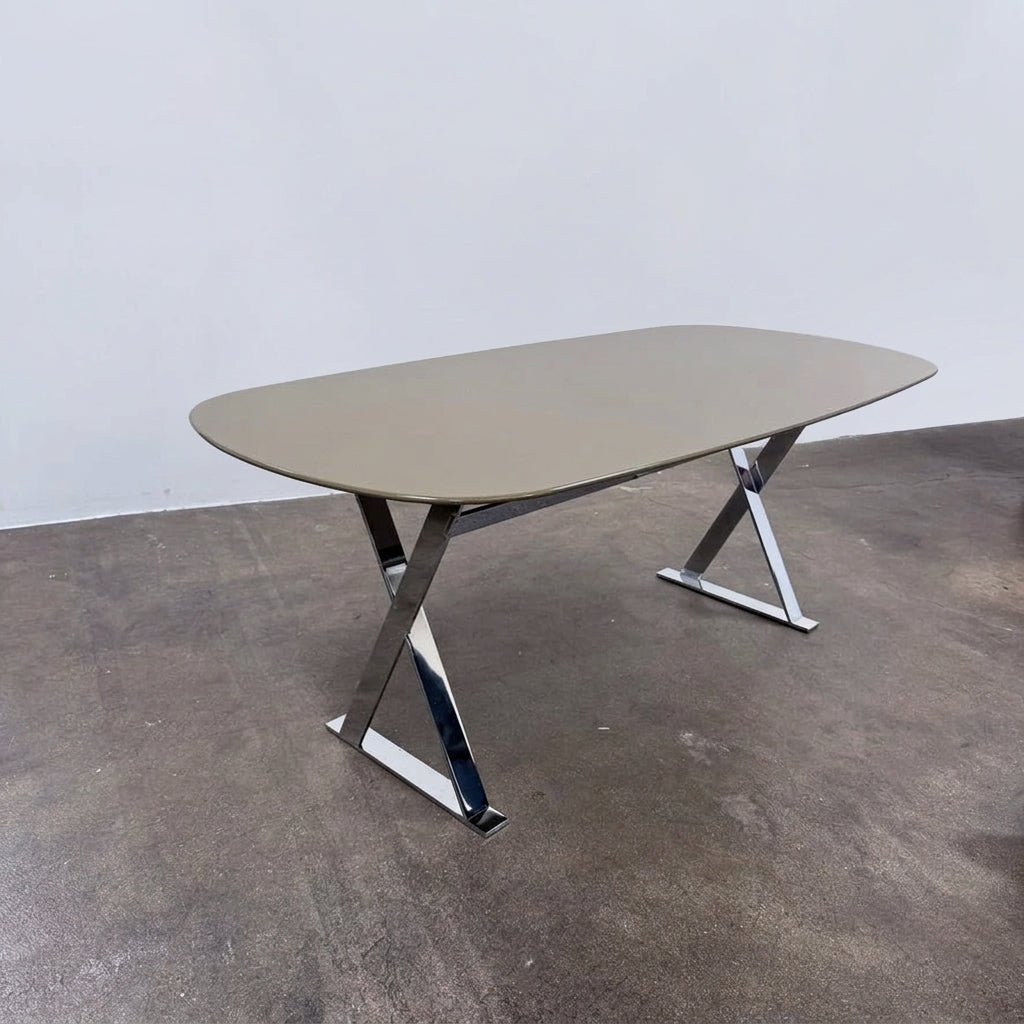 Maxalto Pathos dining table featuring an oval dark top and a contemporary elegant X-shaped chrome frame.
