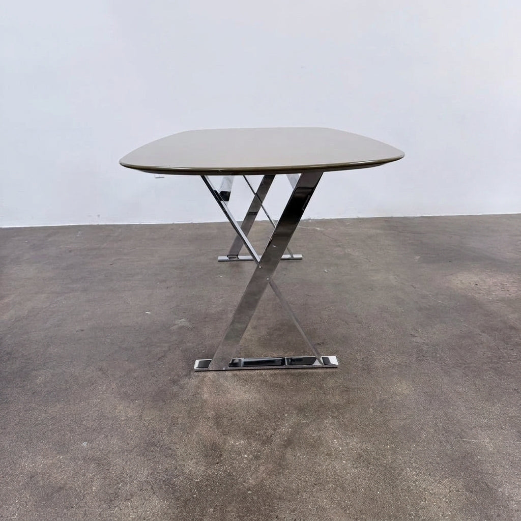Maxalto Pathos dining table featuring an oval dark top and a contemporary elegant X-shaped chrome frame.