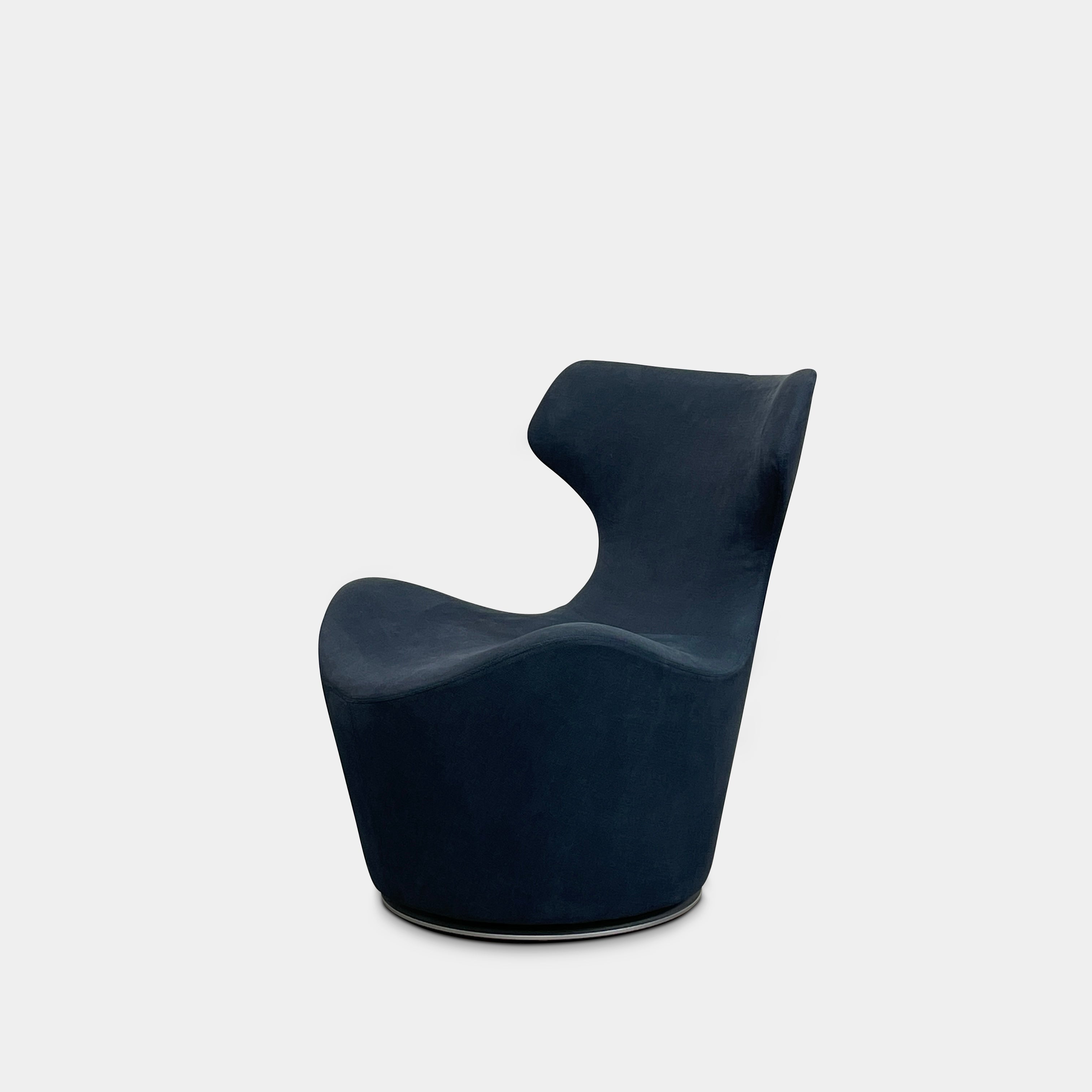 The B&B Italia Piccola Papilio Swivel Armchair is a modern piece with an abstract form and high curved backrest. Made from teal fabric, it stands on a swivel base against a plain white background.