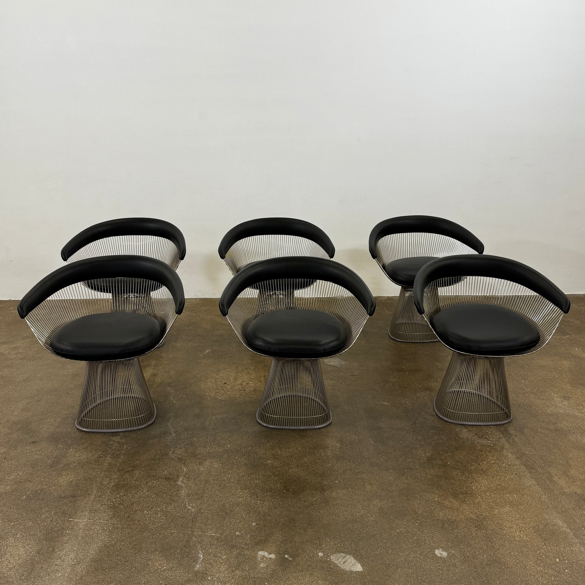 A set of six Knoll Platner Armchairs by Knoll, featuring black seats and backs with metal wire bases, inspired by modernist design, arranged in two rows against a plain white background.