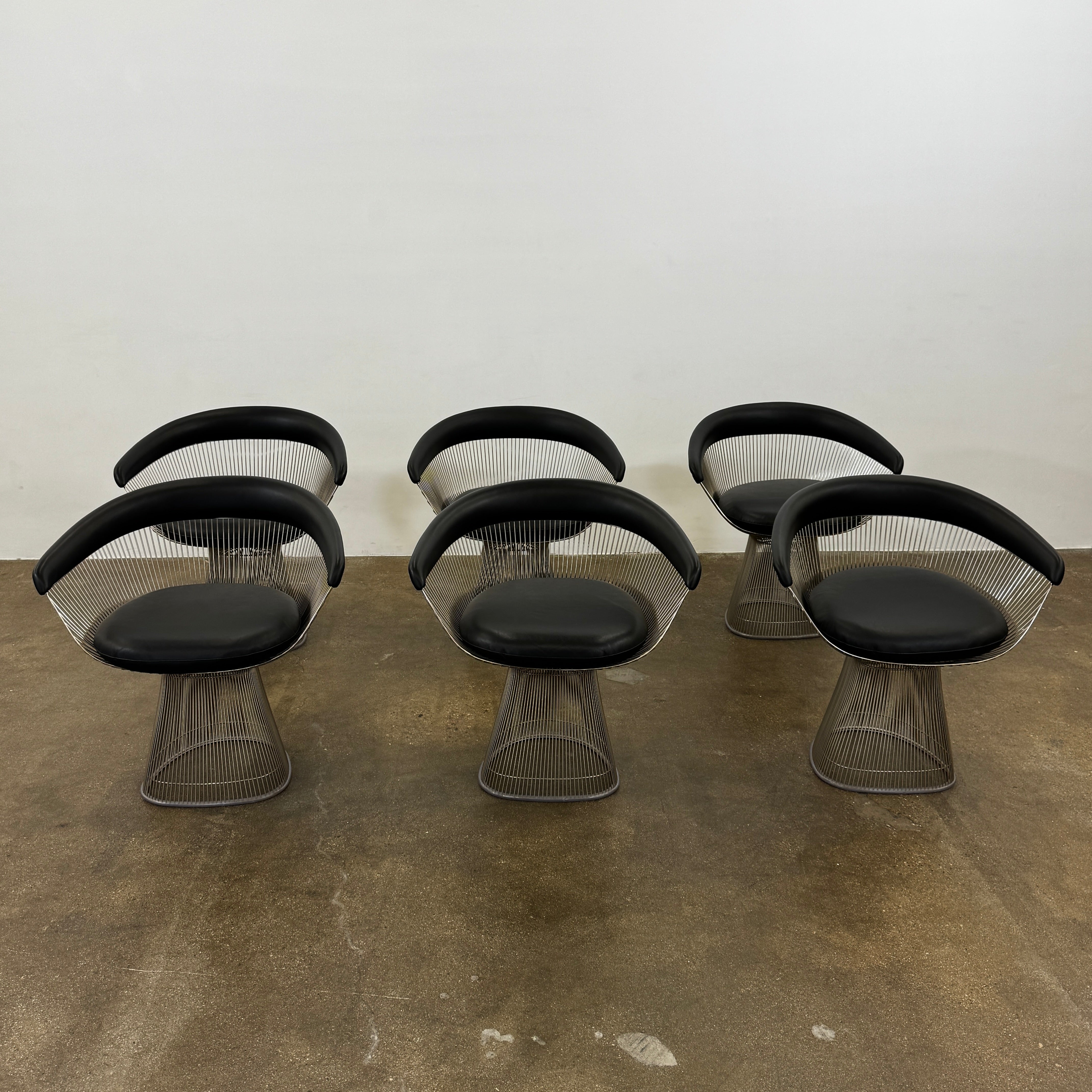 A set of six Knoll Platner Armchairs by Knoll, featuring black seats and backs with metal wire bases, inspired by modernist design, arranged in two rows against a plain white background.