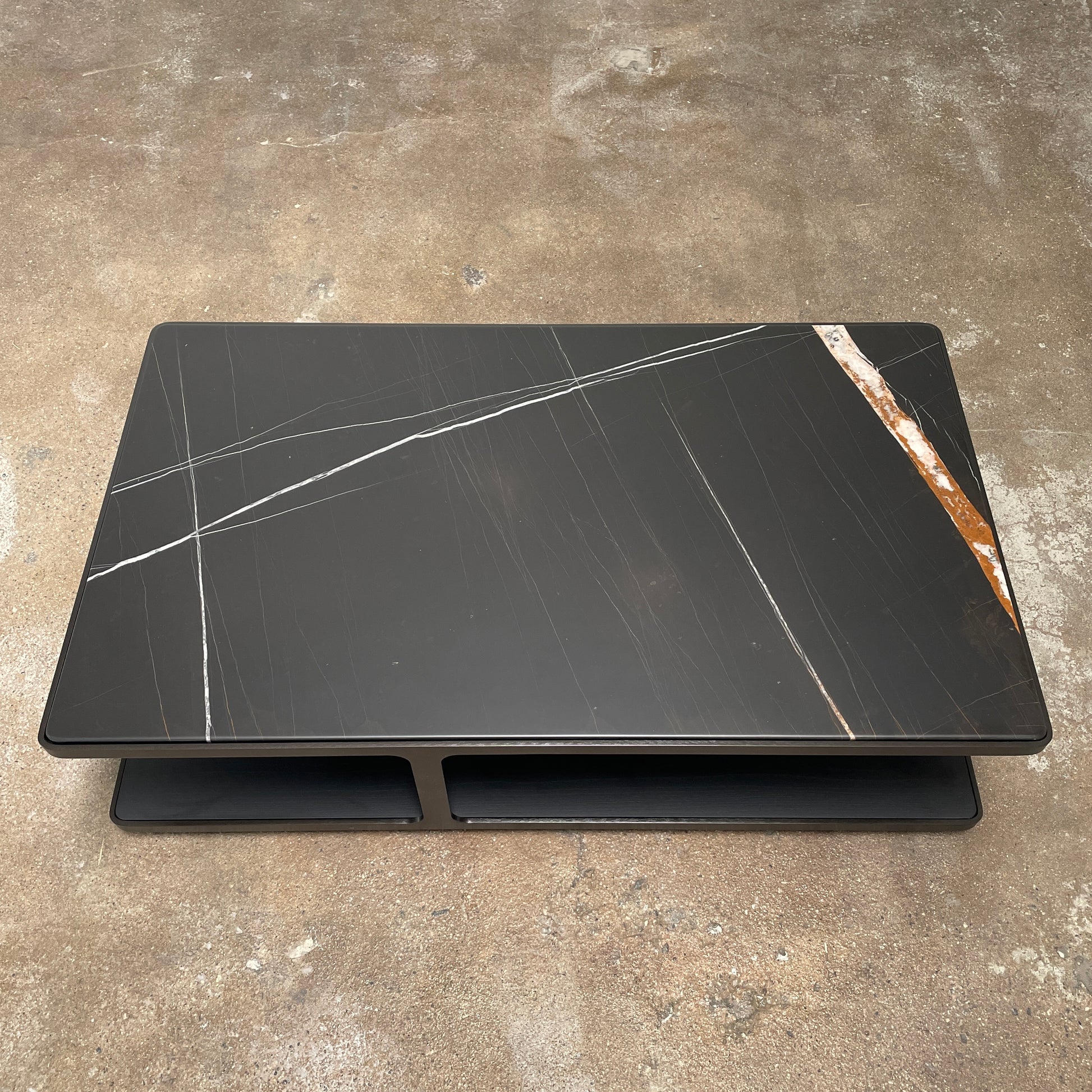 The Poliform Creek Marble Coffee Table is a rectangular Sahara Noir marble piece with a thin, horizontal design and subtle veining.