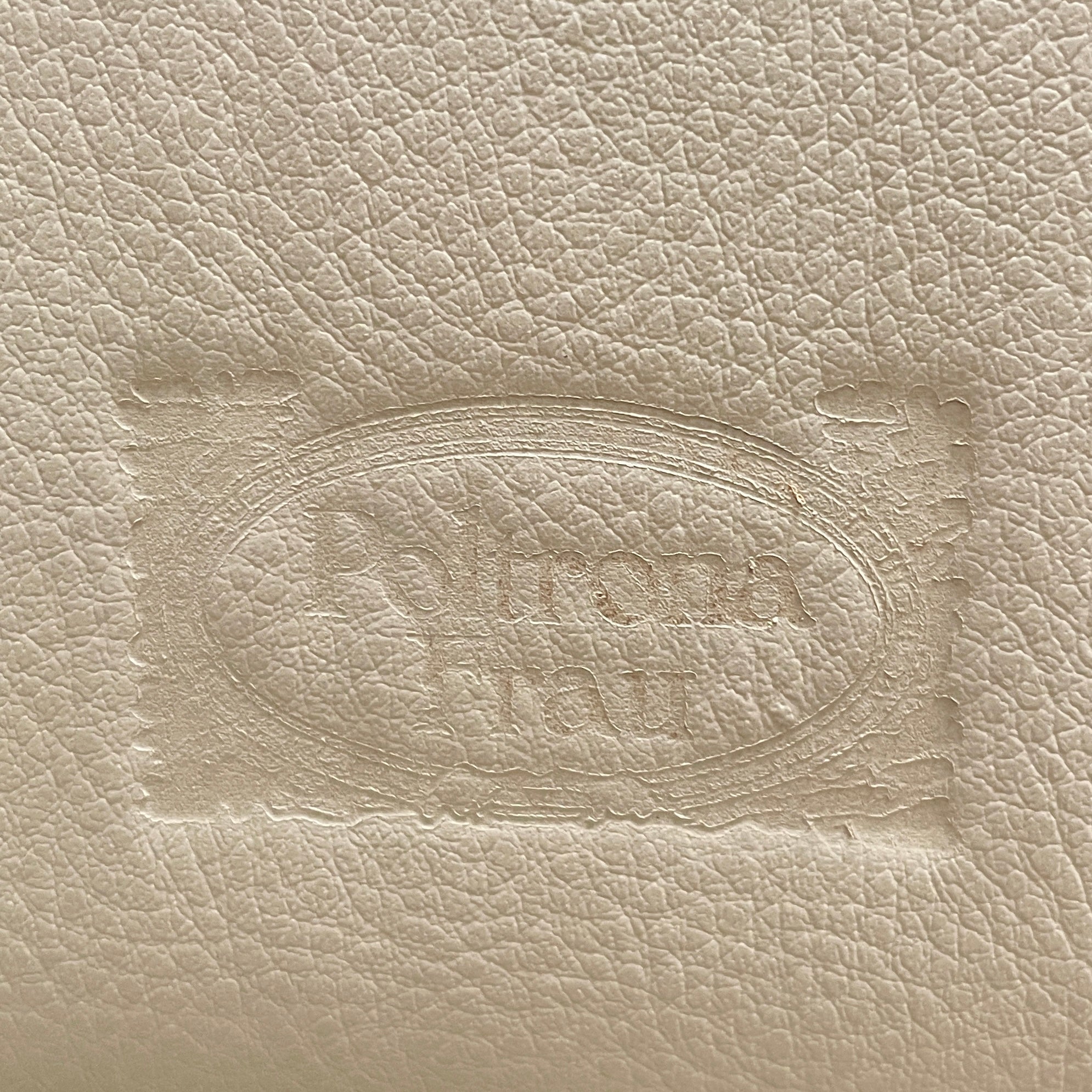 The Poltrona Frau Aurora Due King Bed, crafted by designer Tito Agnoli, boasts a minimalist and modern style with its beige tufted headboard set against a plain light gray wall.