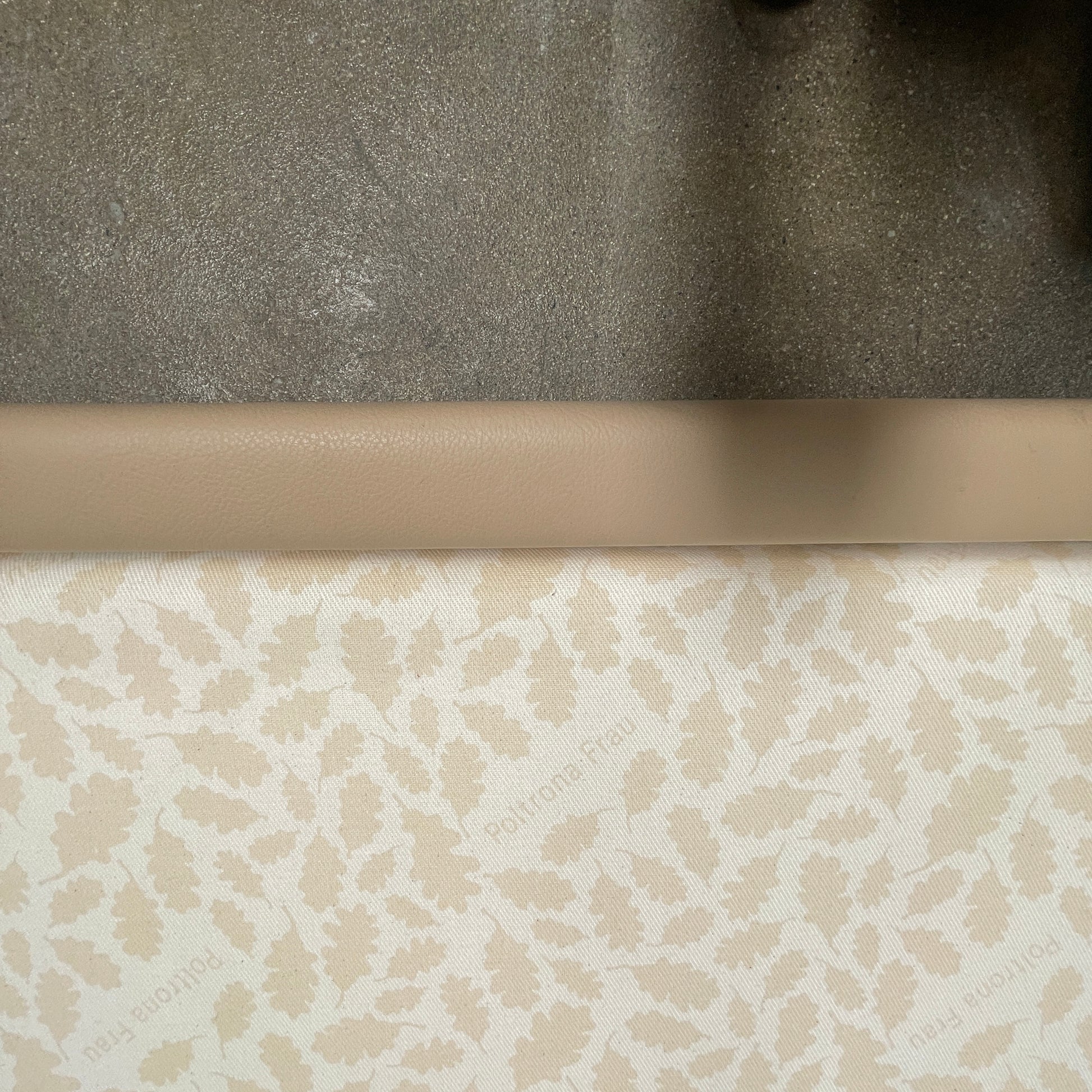 The Poltrona Frau Aurora Due King Bed, crafted by designer Tito Agnoli, boasts a minimalist and modern style with its beige tufted headboard set against a plain light gray wall.