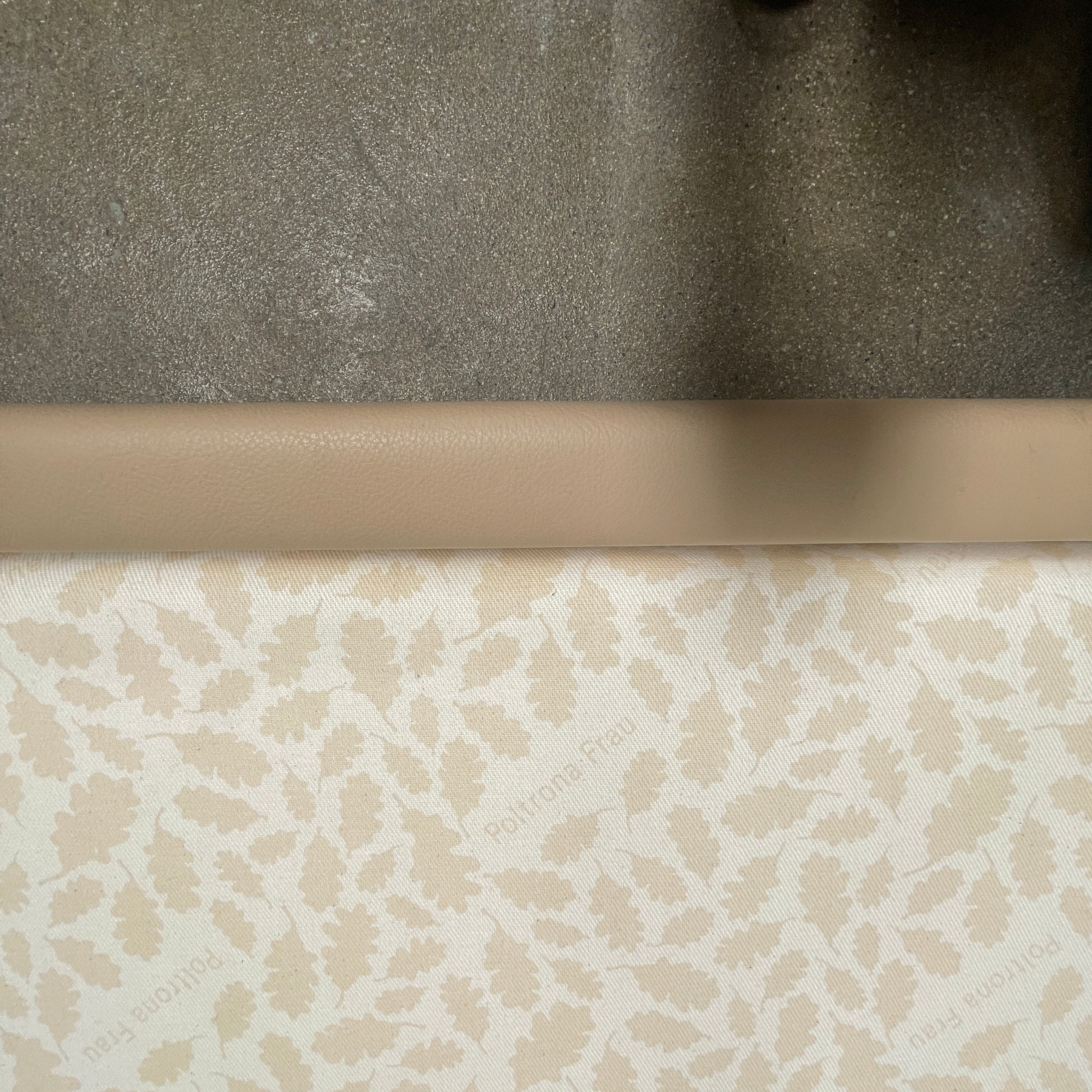 The Poltrona Frau Aurora Due King Bed, crafted by designer Tito Agnoli, boasts a minimalist and modern style with its beige tufted headboard set against a plain light gray wall.