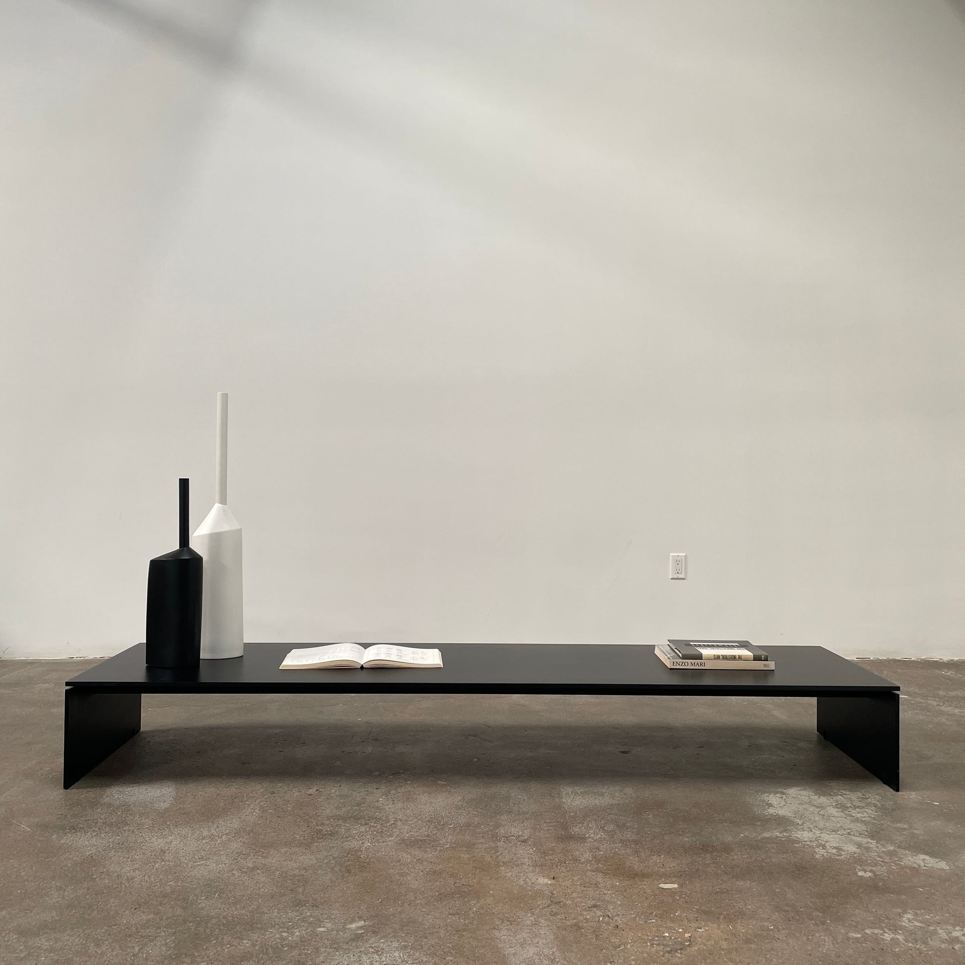 The Porro Modern Light Low Table by Piero Lissoni showcases a minimalist black design with a sleek metal structure and simple, rectangular legs, set against a plain background.