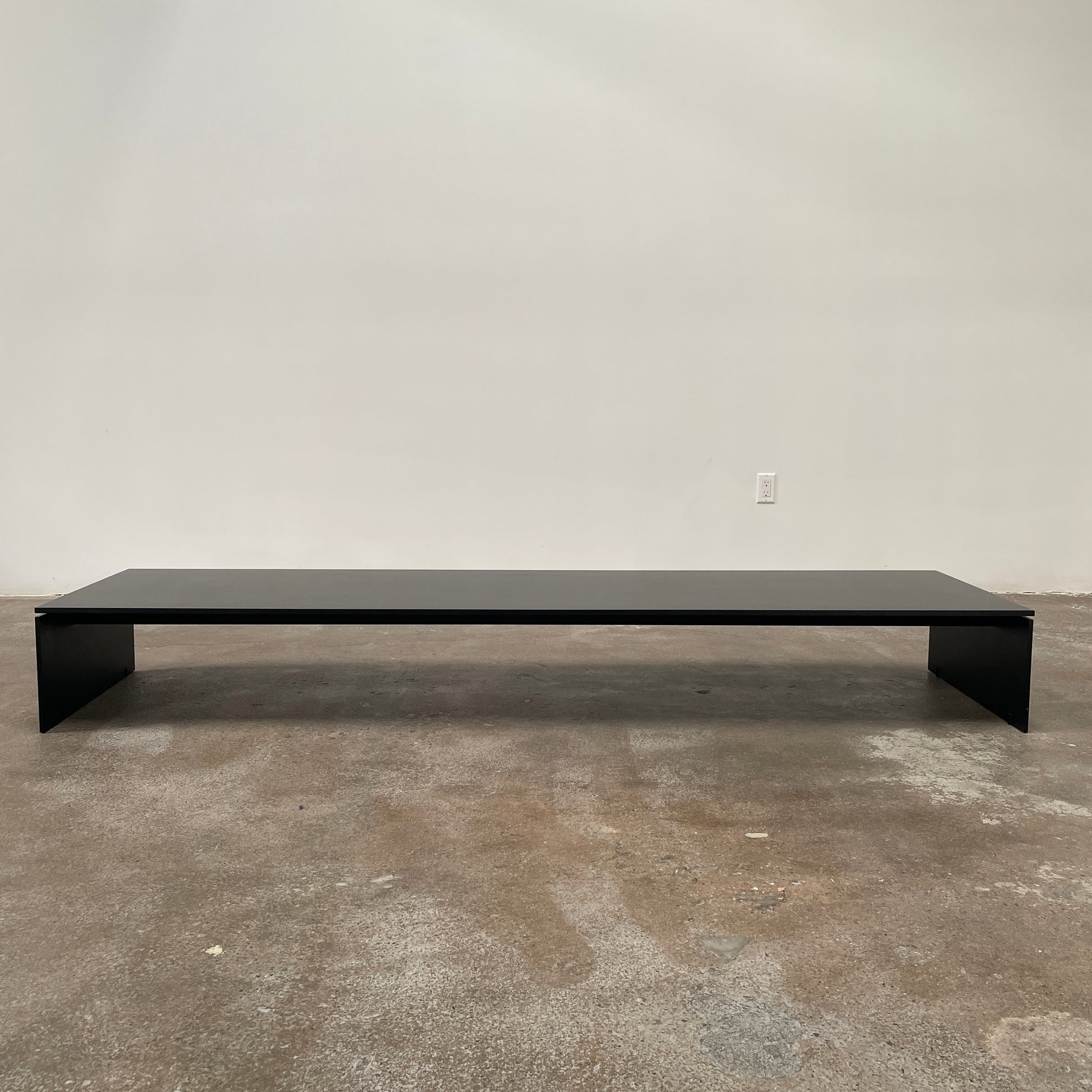 The Porro Modern Light Low Table by Piero Lissoni showcases a minimalist black design with a sleek metal structure and simple, rectangular legs, set against a plain background.