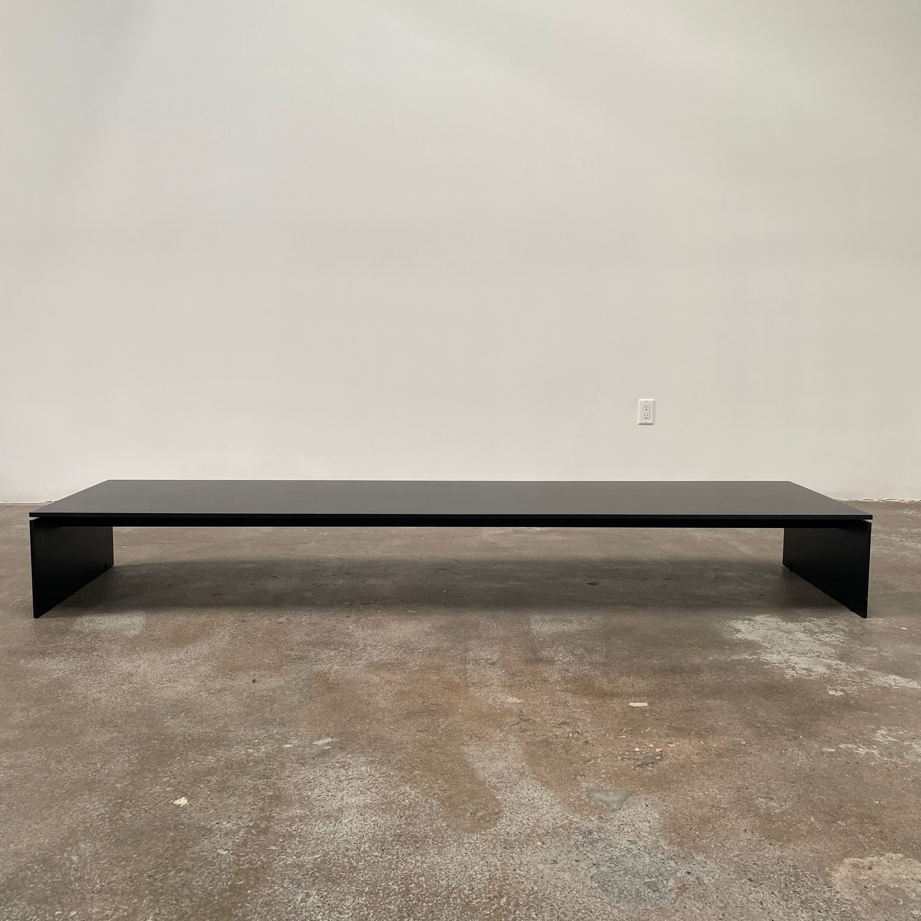 The Porro Modern Light Low Table by Piero Lissoni showcases a minimalist black design with a sleek metal structure and simple, rectangular legs, set against a plain background.