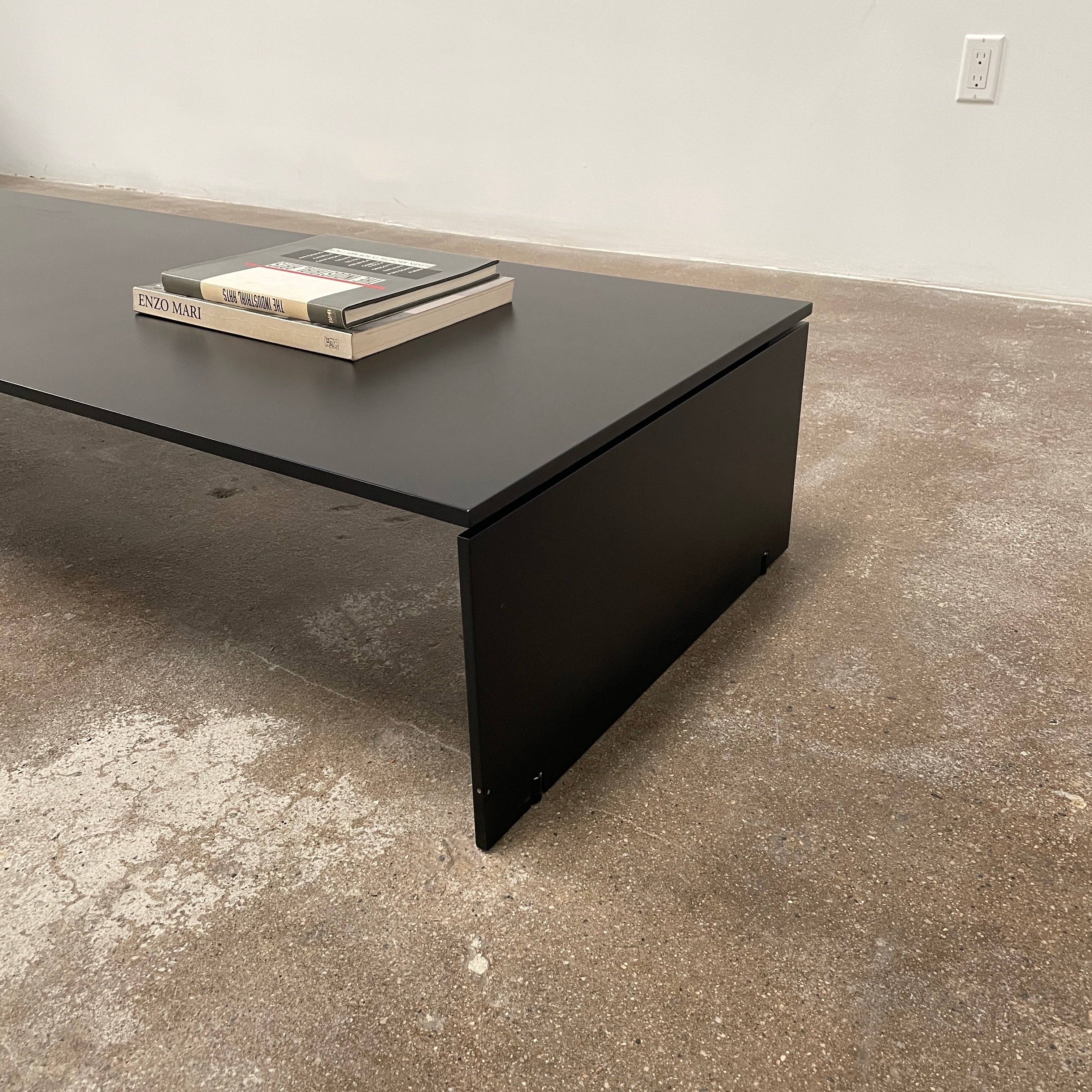 The Porro Modern Light Low Table by Piero Lissoni showcases a minimalist black design with a sleek metal structure and simple, rectangular legs, set against a plain background.