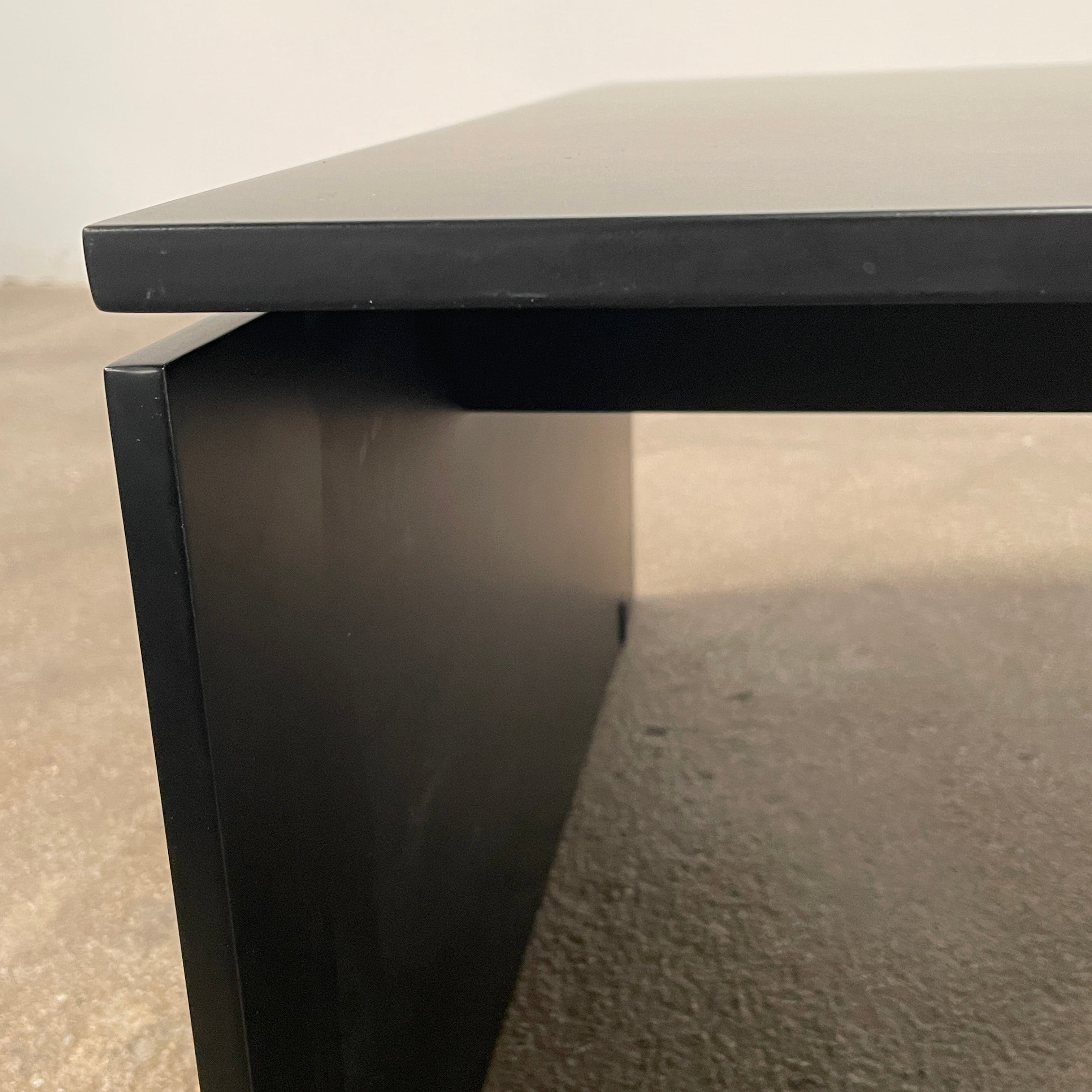 The Porro Modern Light Low Table by Piero Lissoni showcases a minimalist black design with a sleek metal structure and simple, rectangular legs, set against a plain background.