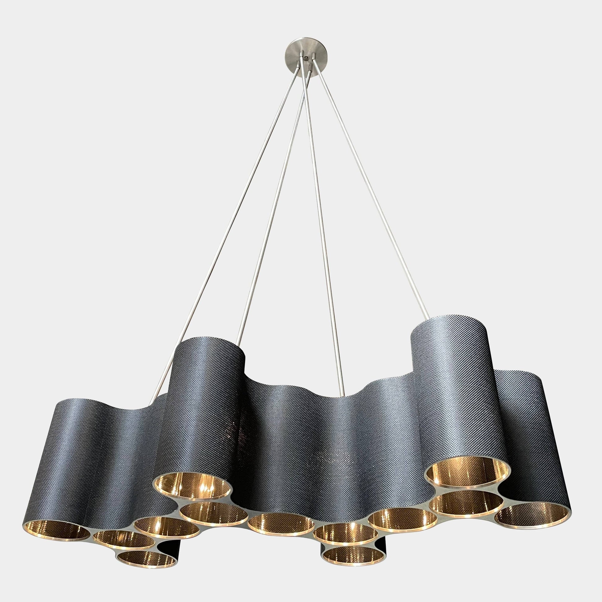 A modern metal chandelier with multiple cylindrical shades connected by thin, curved attachments, hanging from a ceiling mount—a design reminiscent of the Ralph Pucci Linear Cumulus Ceiling Light.