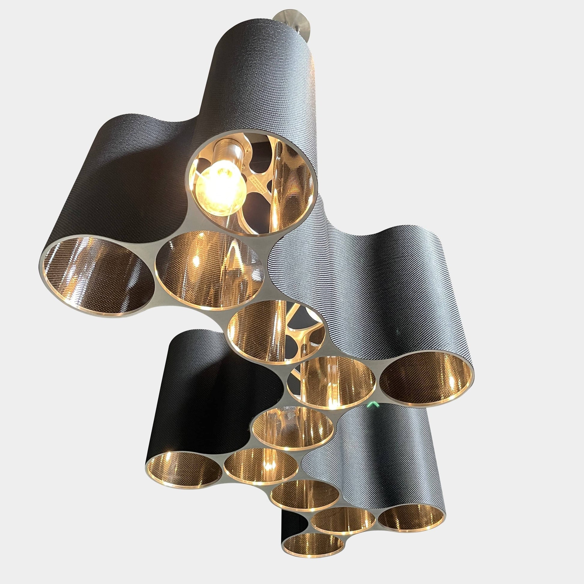 A modern metal chandelier with multiple cylindrical shades connected by thin, curved attachments, hanging from a ceiling mount—a design reminiscent of the Ralph Pucci Linear Cumulus Ceiling Light.