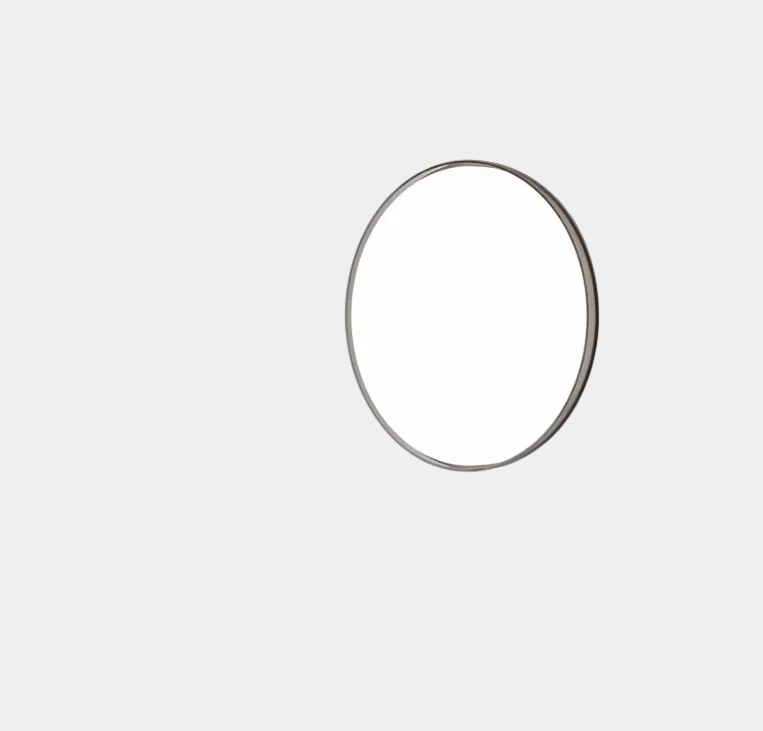 A round, frameless mirror is mounted on a light gray wall, complemented by the Flos Clara Flush-mounted Wall Ceiling LED Light, enhancing the clean and minimalist aesthetic.