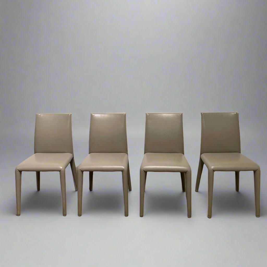 Six B&B Italia Vol au Vent Dining Chairs, embodying the elegance of Italian style, are arranged in two rows in an empty room with a concrete floor and a plain white wall.
