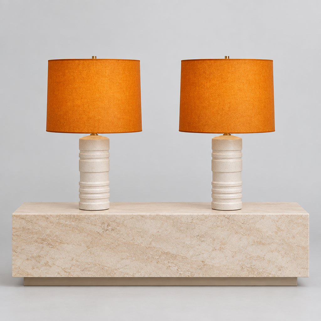Two Shelter Brasilia Lamp by Modern Resale with textured white bases and orange cylindrical shades are displayed on a beige stone surface against a gray background.