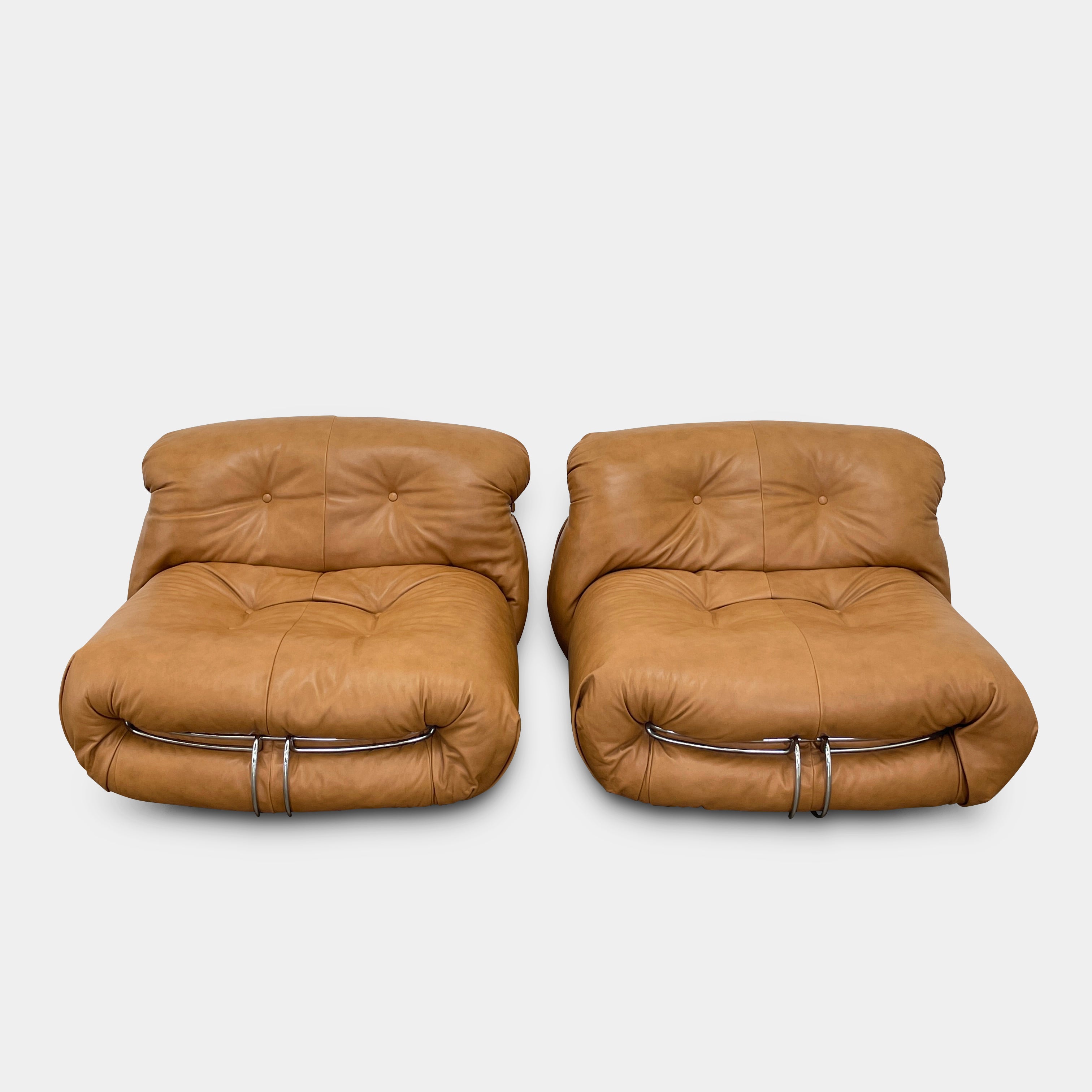 A set of two tan leather lounge chairs, echoing the vintage 1970s Cassina Soriana designs by Afra & Tobia Scarpa, showcases tufted backrests and tubular metal frames on a plain white background.
