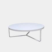 A round Tacchini Cage Coffee Table, White by Tacchini with thin metal legs stands on a plain gray concrete floor against a blank wall.