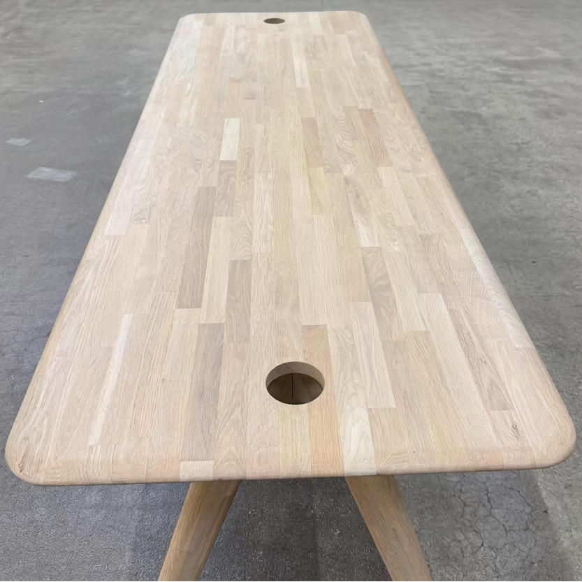Tom Dixon Slab Desk/Table with cord management featuring a light-colored solid oak slab with rounded corners and circular cord management ports on each end.