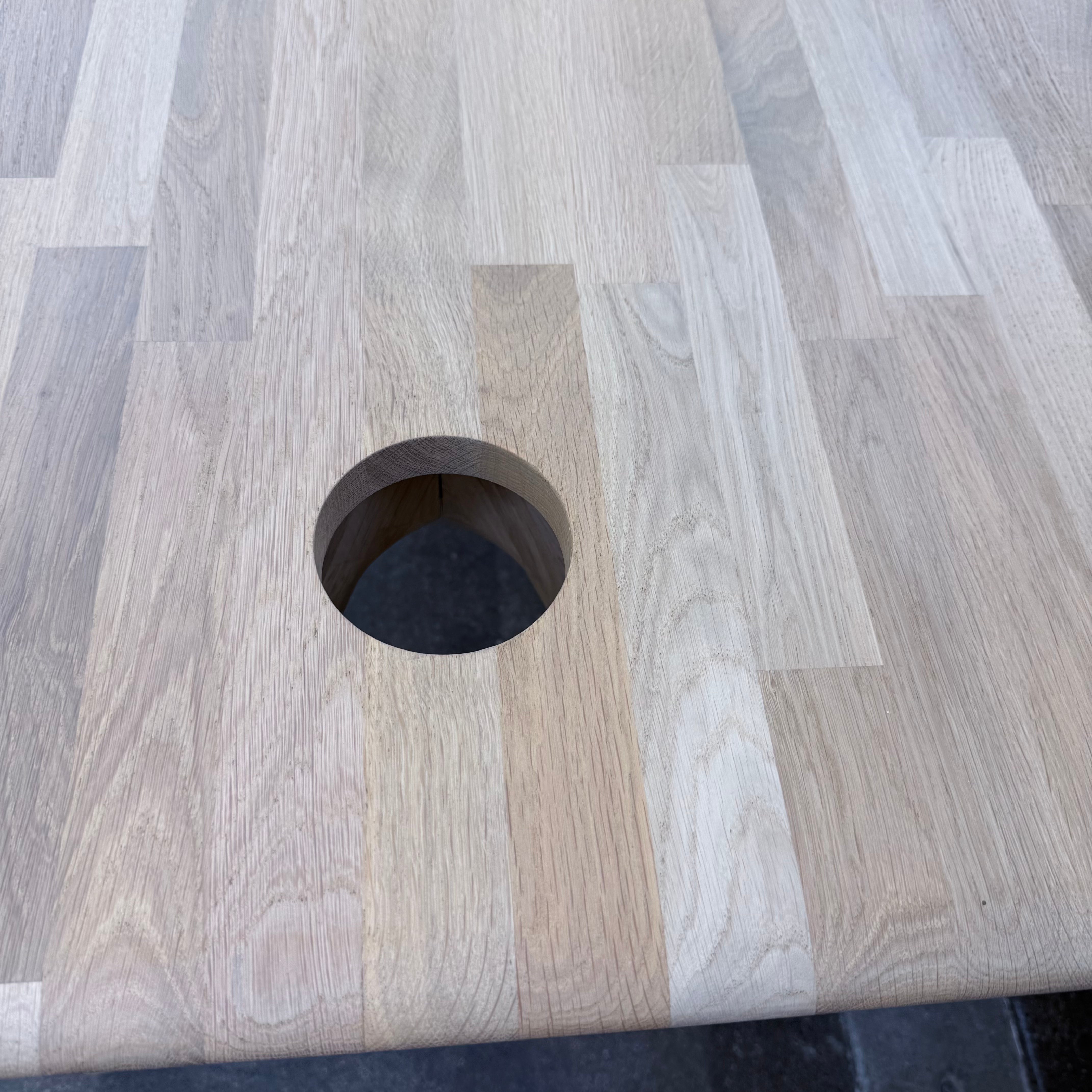 Tom Dixon Slab Desk/Table with cord management featuring a light-colored solid oak slab with rounded corners and circular cord management ports on each end.