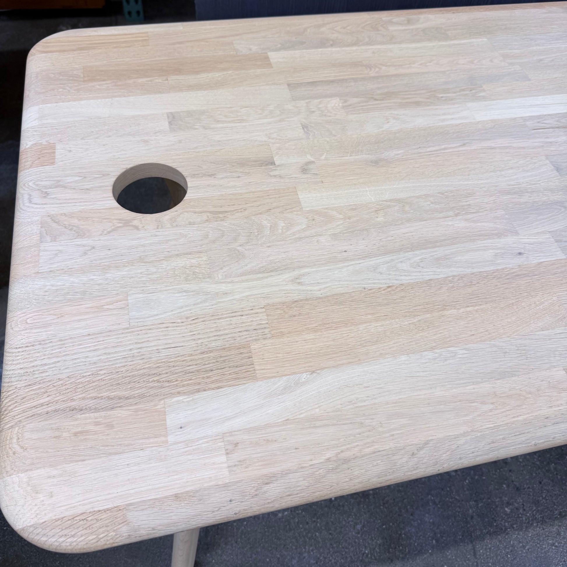 Tom Dixon Slab Desk/Table with cord management featuring a light-colored solid oak slab with rounded corners and circular cord management ports on each end.