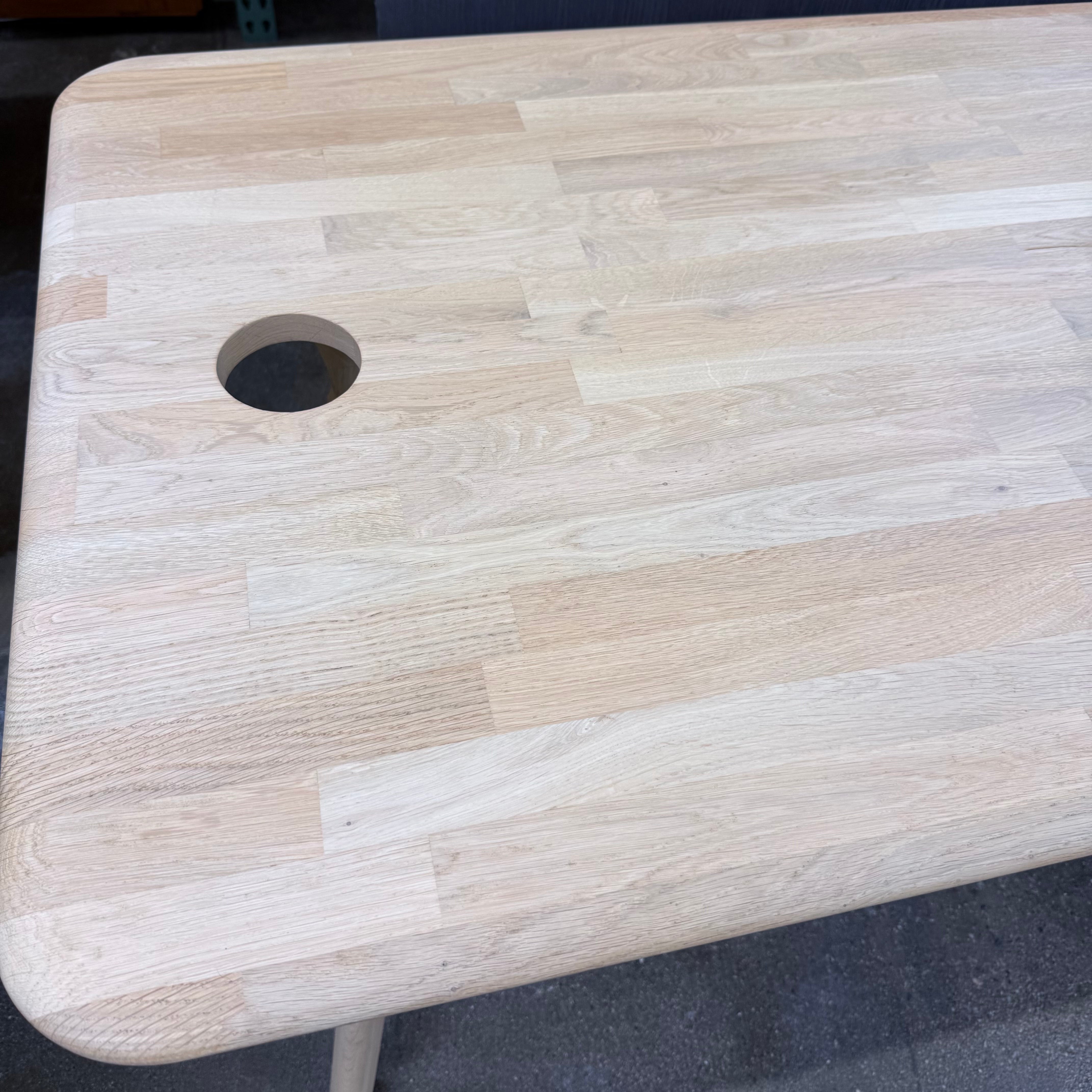 Tom Dixon Slab Desk/Table with cord management featuring a light-colored solid oak slab with rounded corners and circular cord management ports on each end.