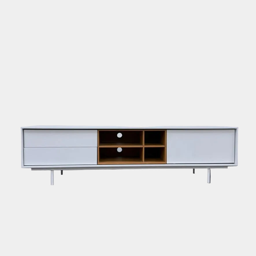 Low-profile white DWR Treku Aura Media Unit on thin legs, featuring two side cabinets and a central open shelf section with a wood-toned interior.
