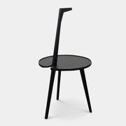 The Cassina Cicognino Side Table by Cassina is black and modern, featuring a round top, three legs, and a vertical handle-like design.