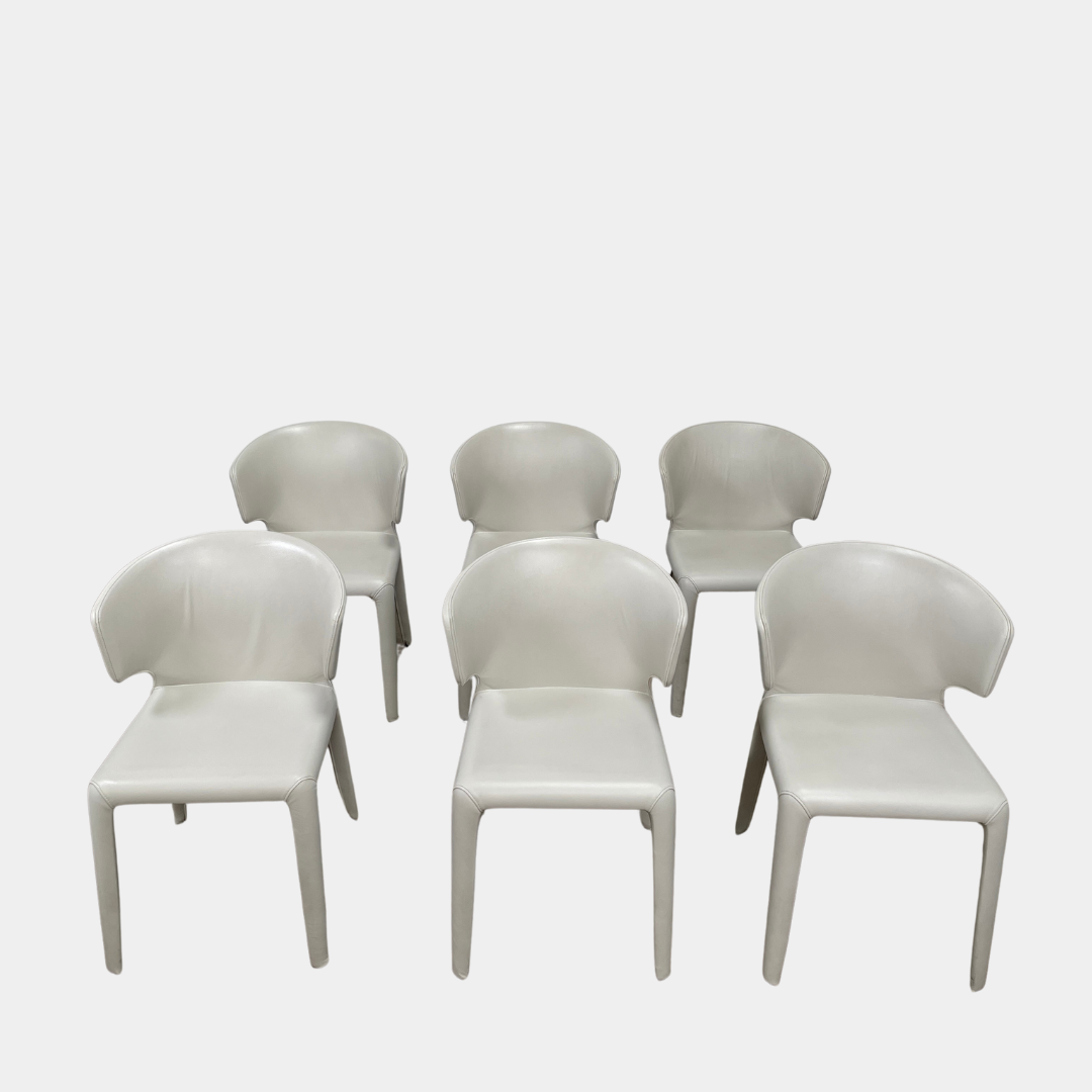Six Cassina Hola 367 Dining Chairs, identical and upholstered in white leather, are elegantly arranged in two rows on a plain background.