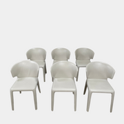 Six Cassina Hola 367 Dining Chairs, identical and upholstered in white leather, are elegantly arranged in two rows on a plain background.
