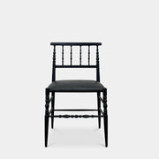 The Cappellini New Antiques Spindle Chair by Marcel Wanders for Cassina, in black wood, showcases a sleek backrest and cushioned seat when viewed from the front.