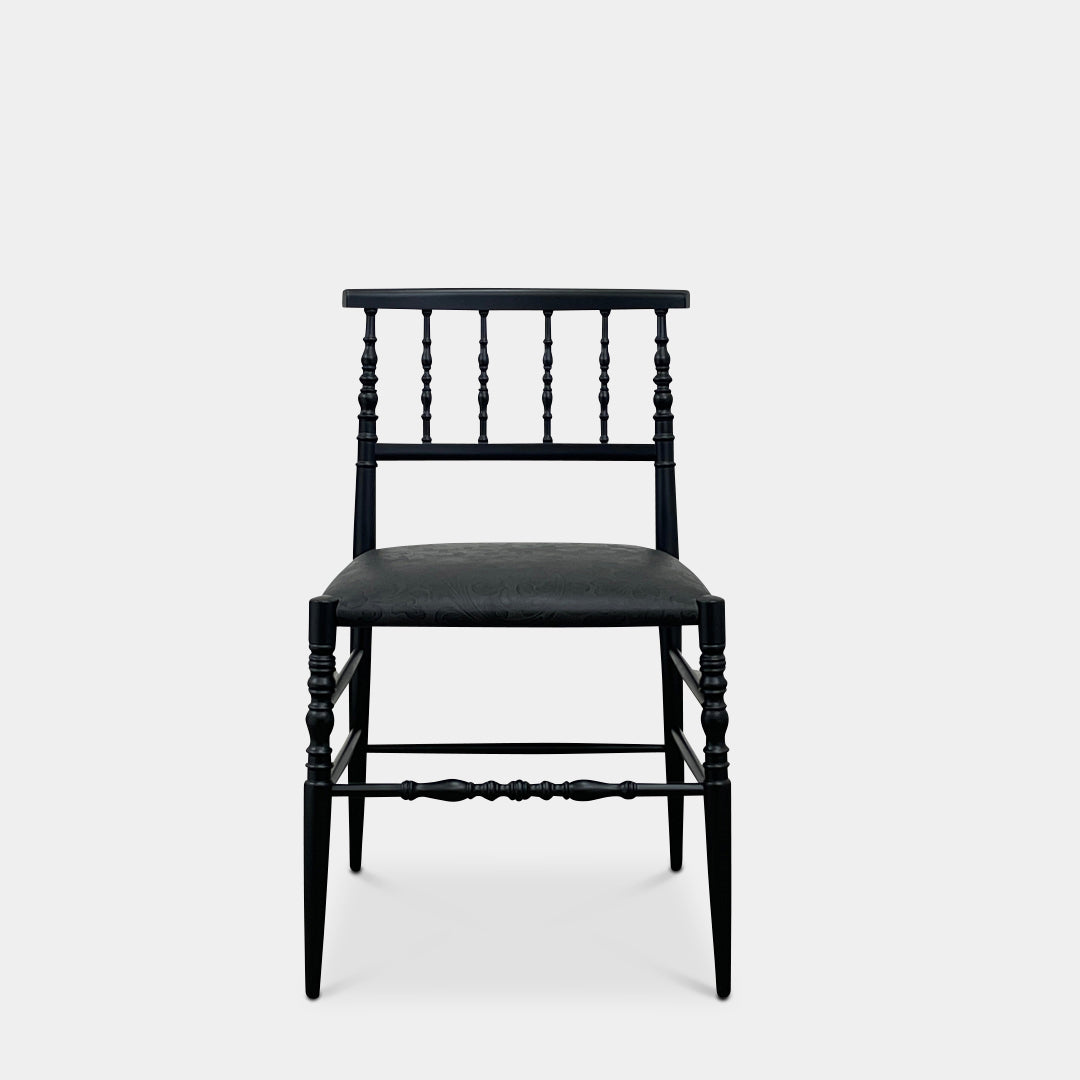 The Cappellini New Antiques Spindle Chair by Marcel Wanders for Cassina, in black wood, showcases a sleek backrest and cushioned seat when viewed from the front.